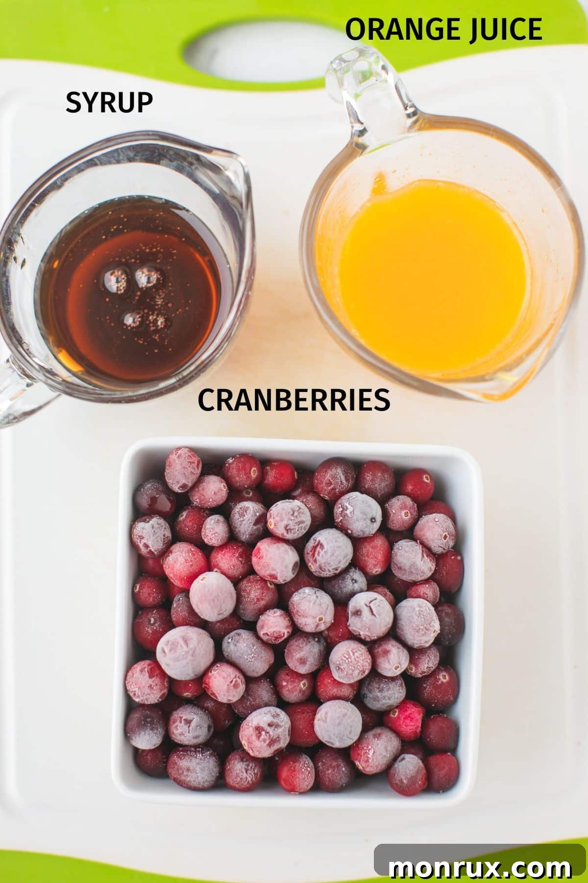 Labeled photo showcasing the three key ingredients for Instant Pot Cranberry Sauce: frozen cranberries, orange juice, and maple syrup.