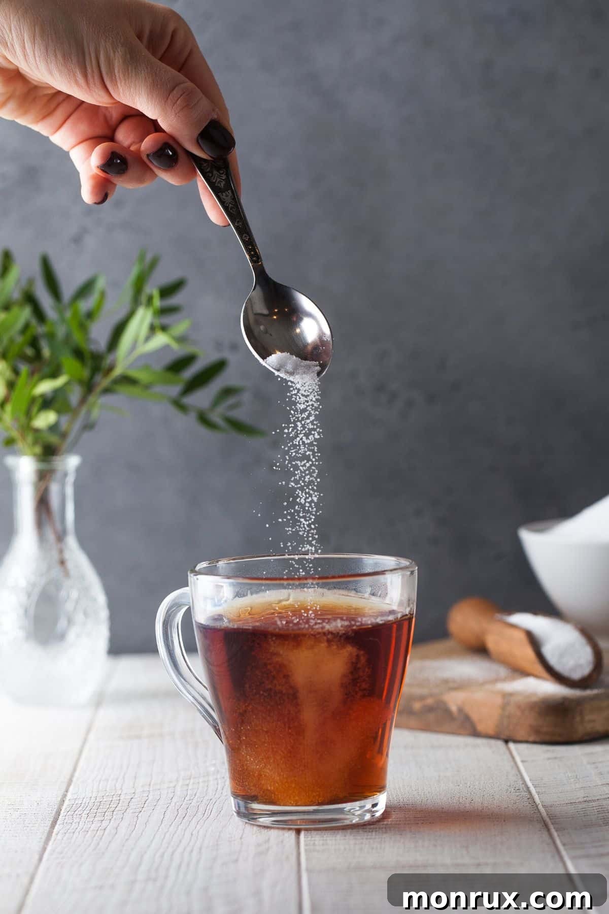 A hand pouring sweetener into a hot drink, illustrating the use of sugar alternatives.