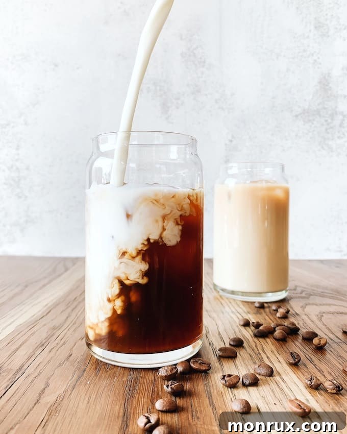 A glass of oat milk next to a cup of coffee, illustrating dairy-free beverage choices.