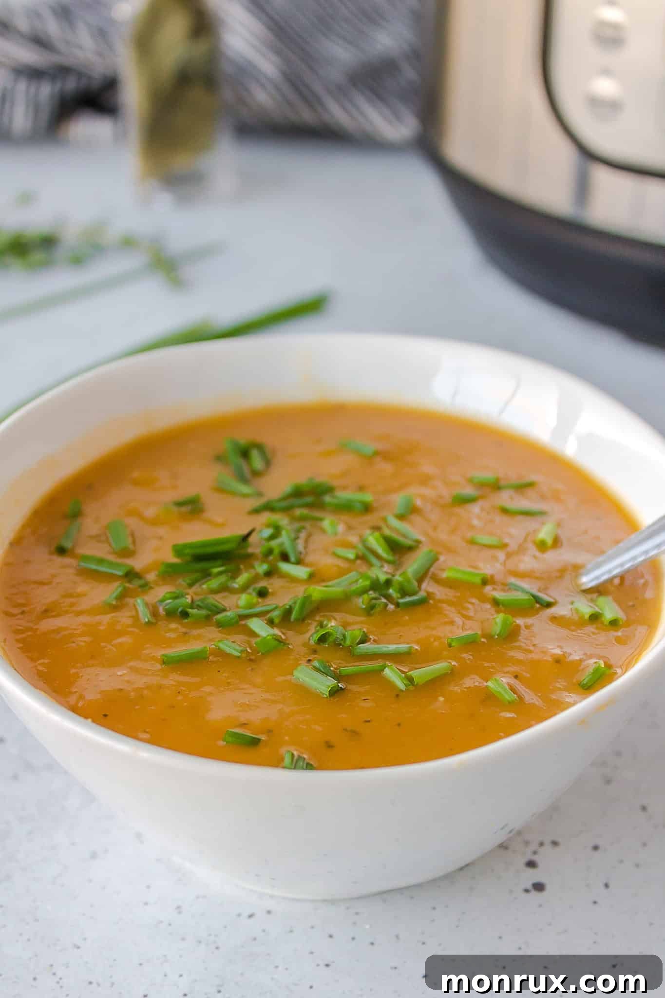 A warm, inviting bowl of creamy vegan potato leek soup garnished with fresh chives.