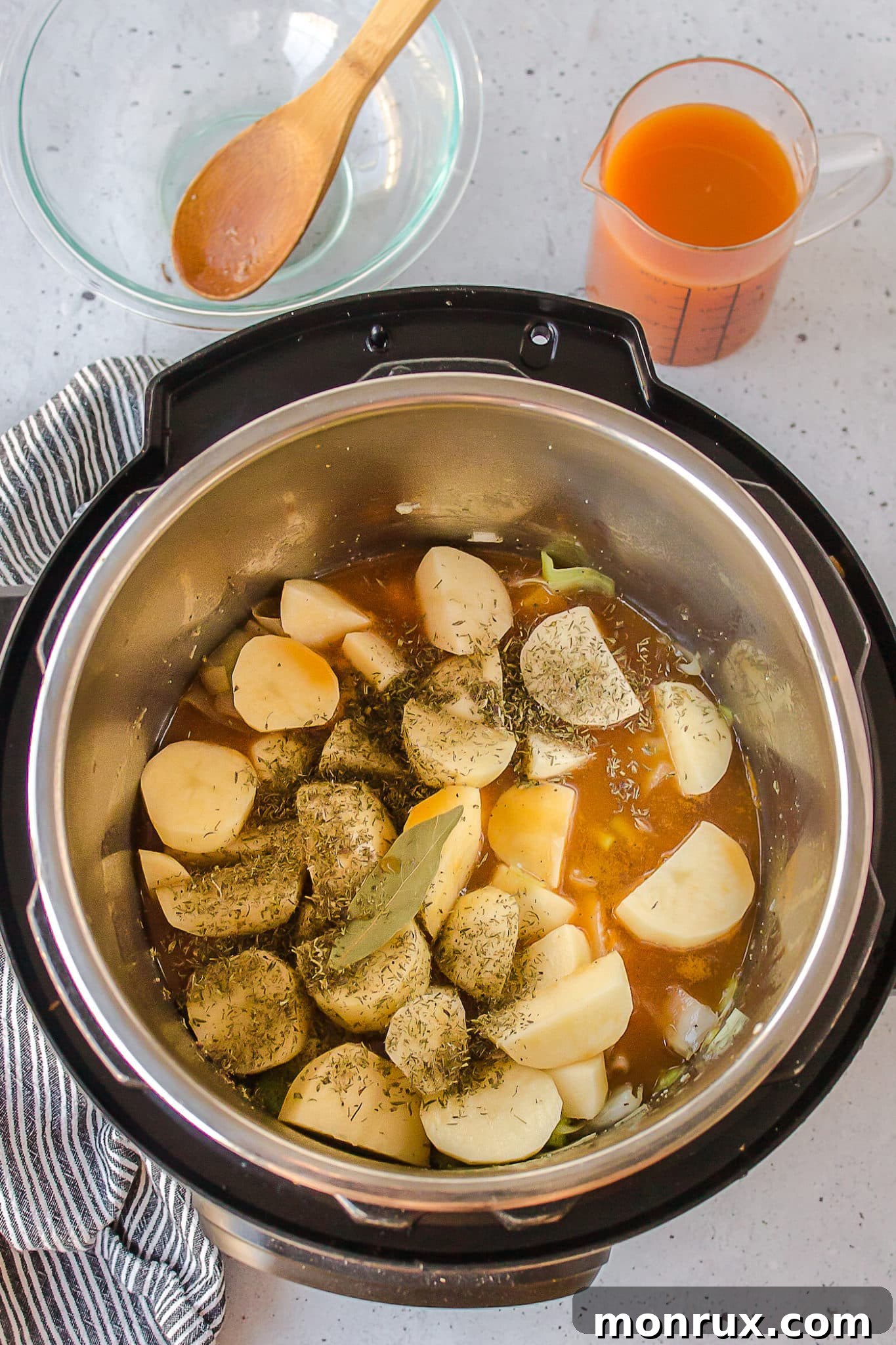 Instant Pot filled with quartered potatoes, chopped leeks, broth, and herbs before cooking.