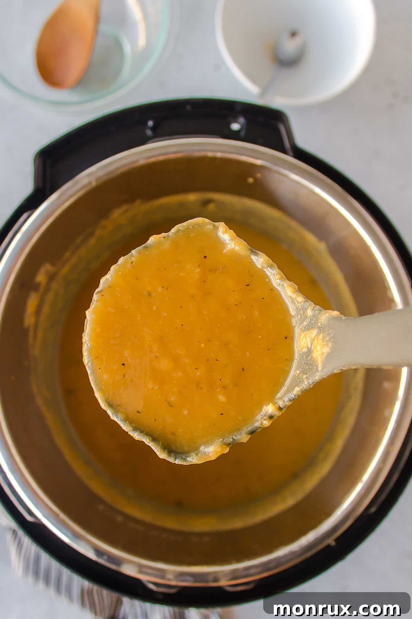 A ladle scooping a creamy portion of vegan potato leek soup from the pot.