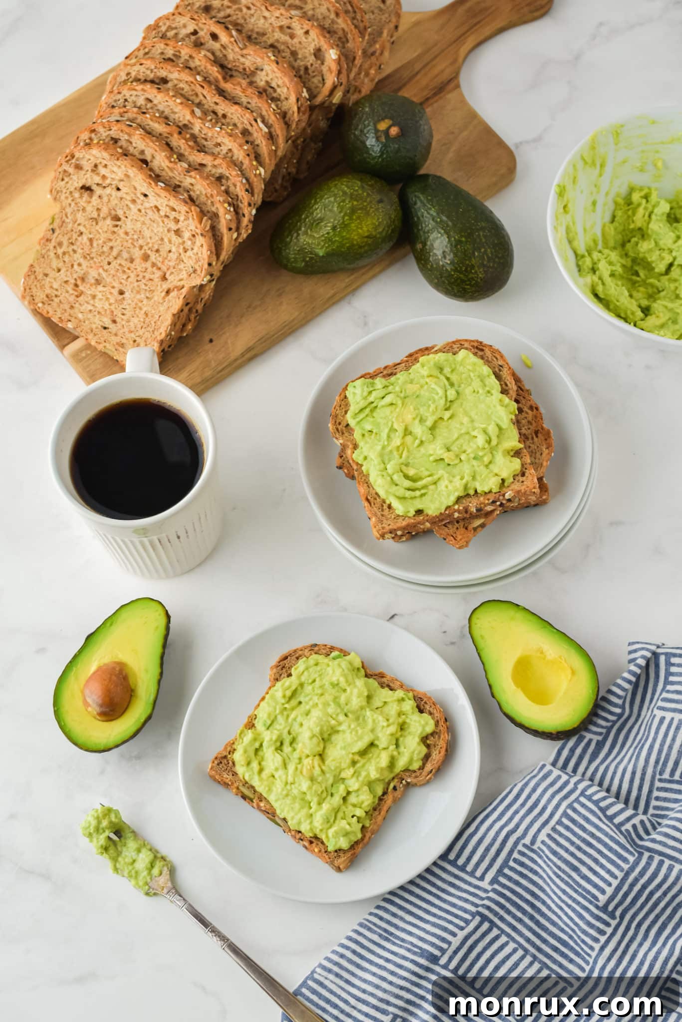 Two plates of perfectly prepared avocado toast, artfully arranged on a table with fresh ingredients nearby, ready to be served.
