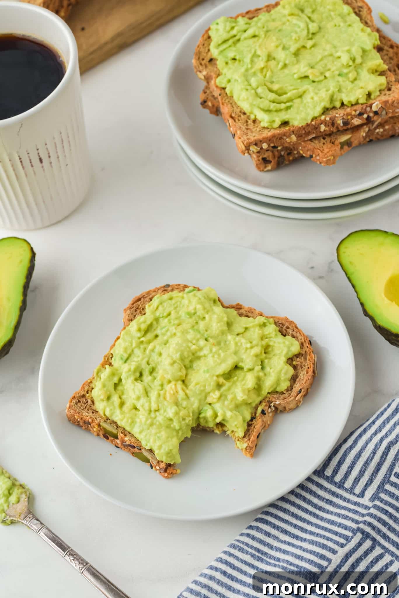 A mug of coffee next to two plates of avocado toast, presented beautifully for a healthy and delicious meal.