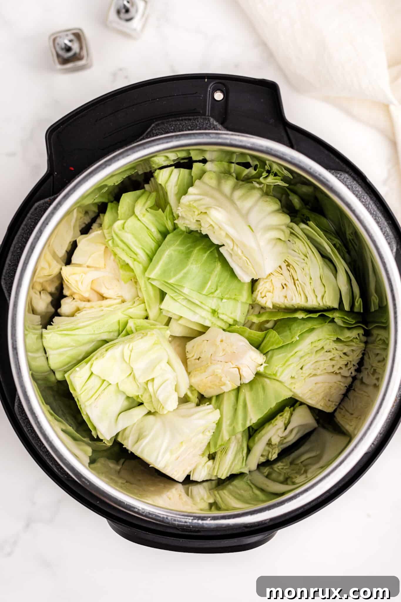 Chopped cabbage neatly placed inside an Instant Pot pressure cooker, ready for the next steps.