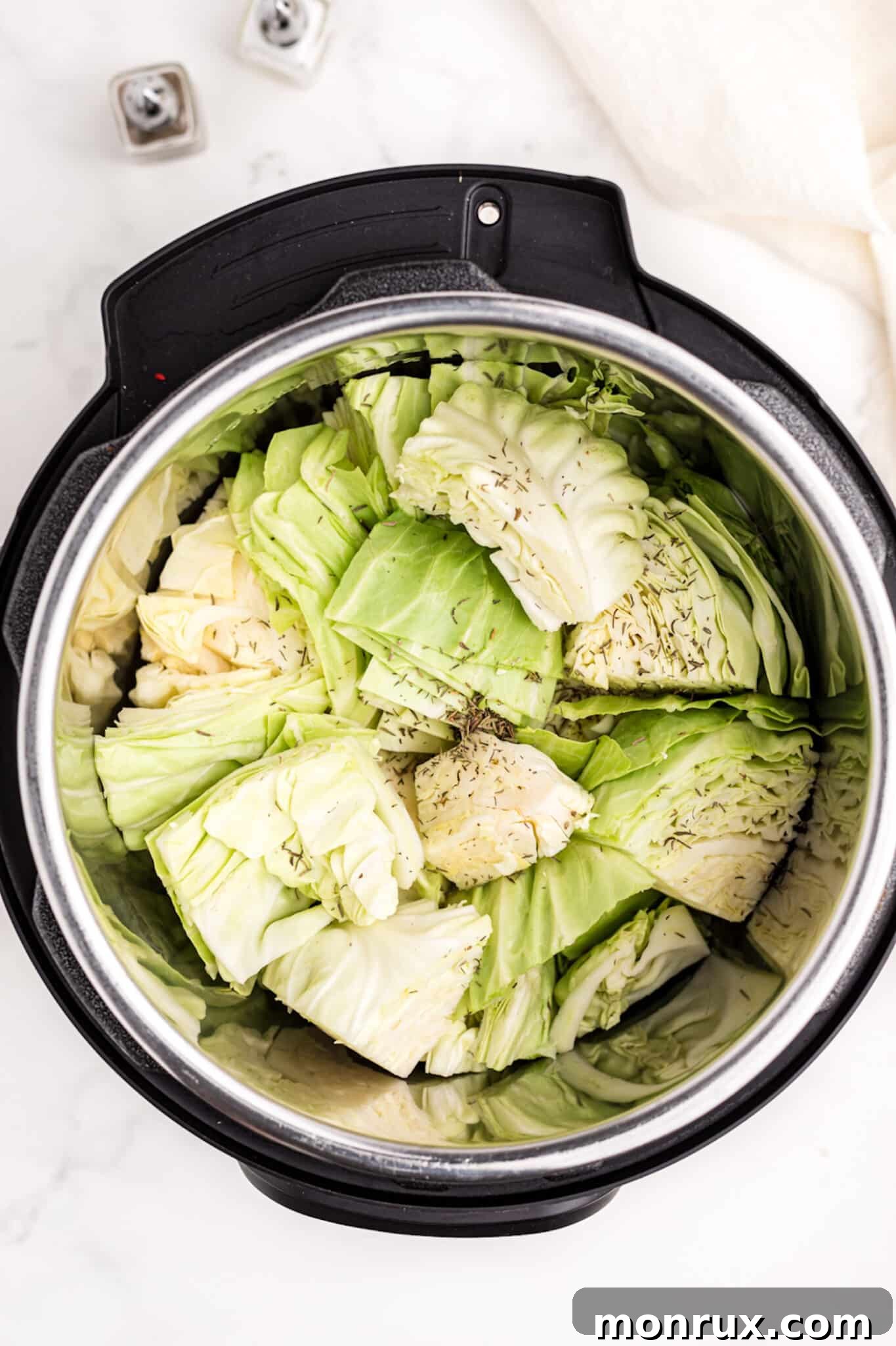 Chopped cabbage inside the Instant Pot, infused with savory broth and aromatic dried herbs.