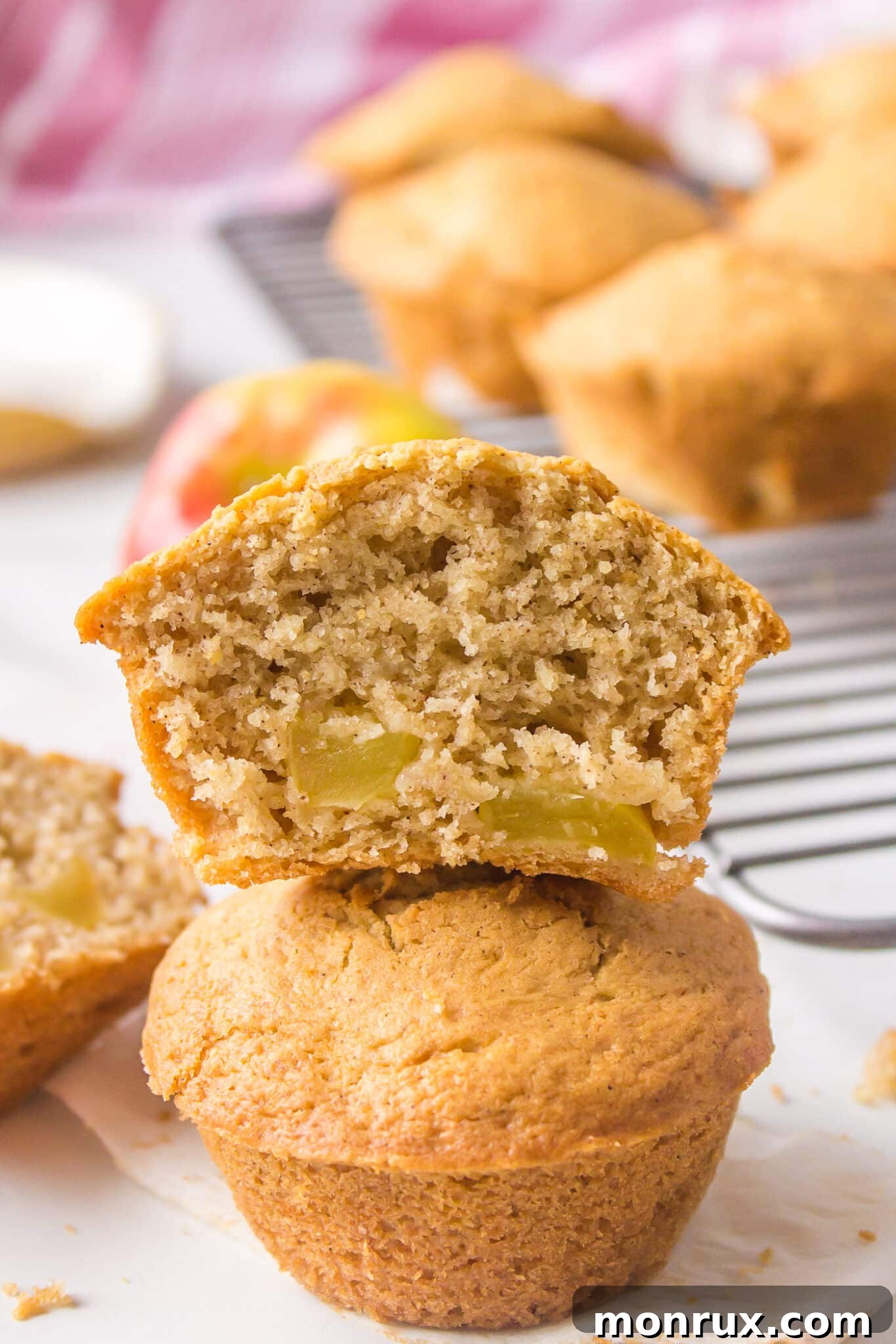 A close-up shot of a halved gluten-free apple muffin stacked on top of a whole muffin, showcasing the tender crumb and apple pieces inside.