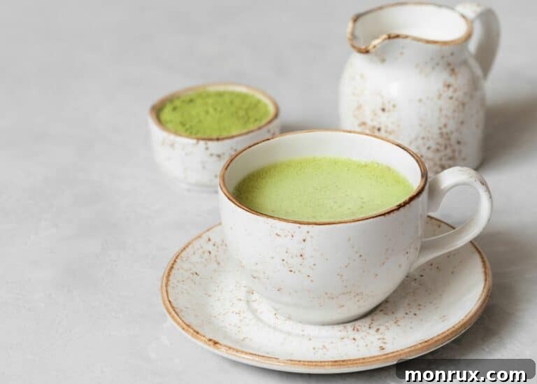 A vibrant green matcha latte served in a rustic ceramic mug on a wooden surface.