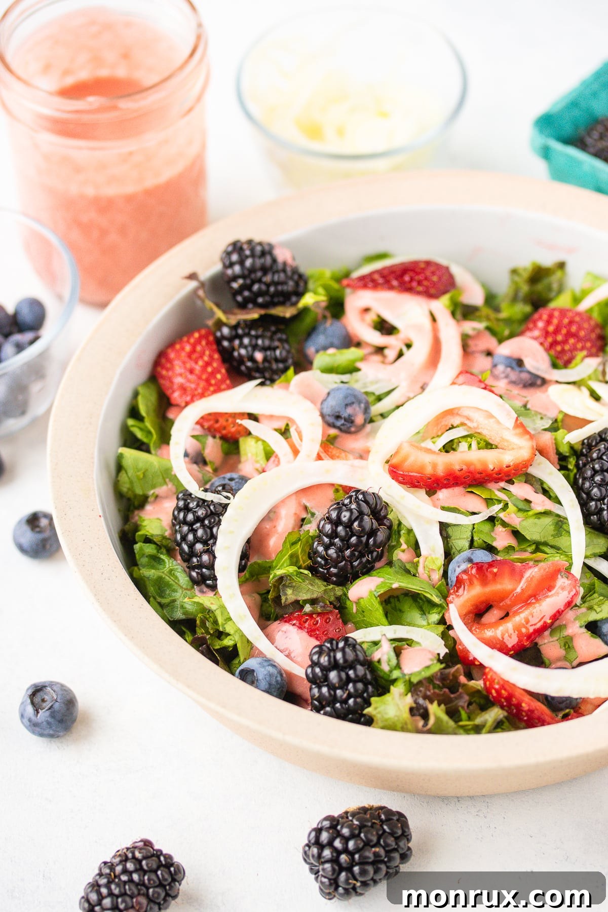 Vibrant green salad topped with a generous drizzle of creamy strawberry salad dressing, garnished with fresh strawberries.