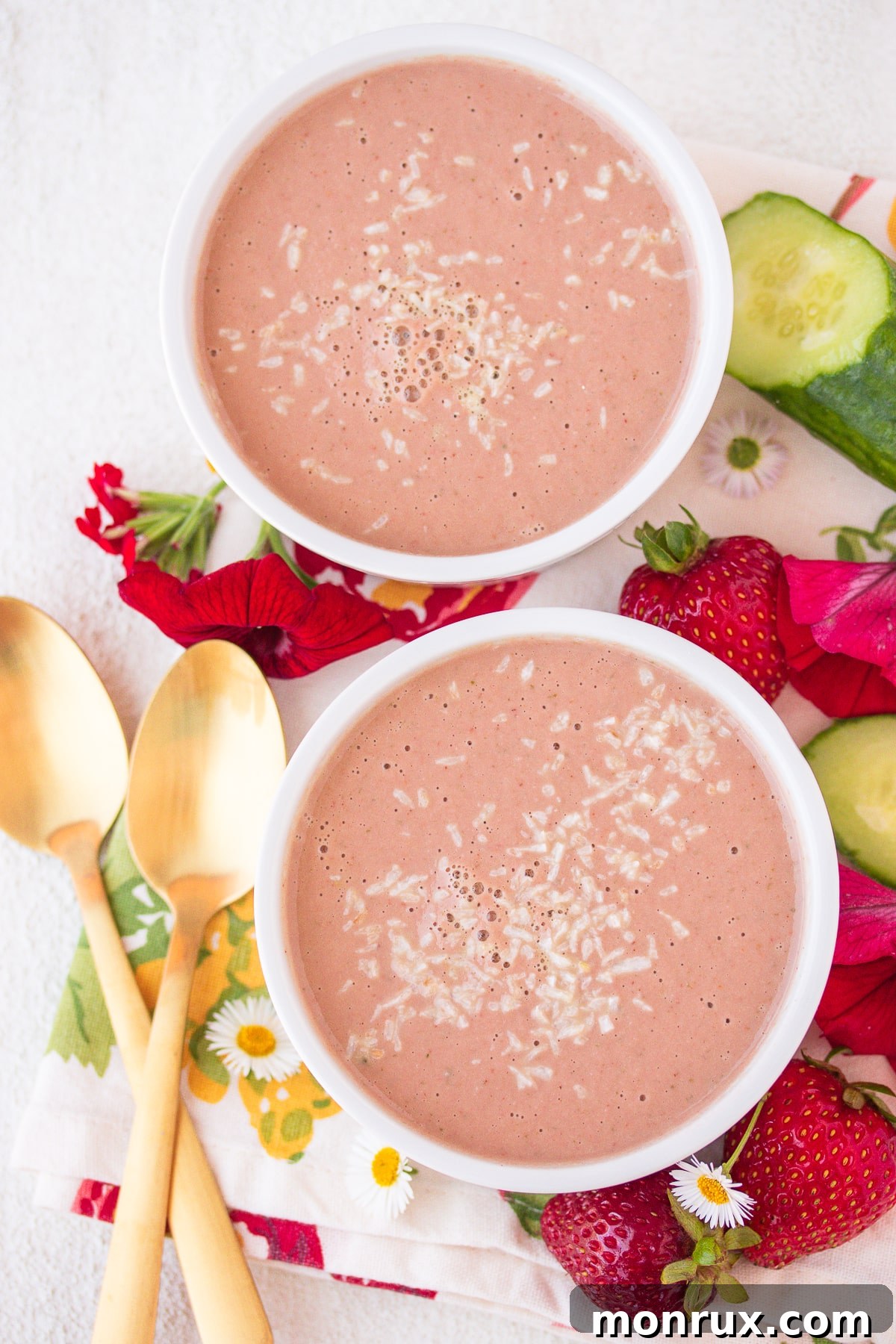 Two aesthetically arranged bowls of cold strawberry soup, garnished with delicate shredded coconut, ready to be enjoyed as a light meal or refreshing dessert.