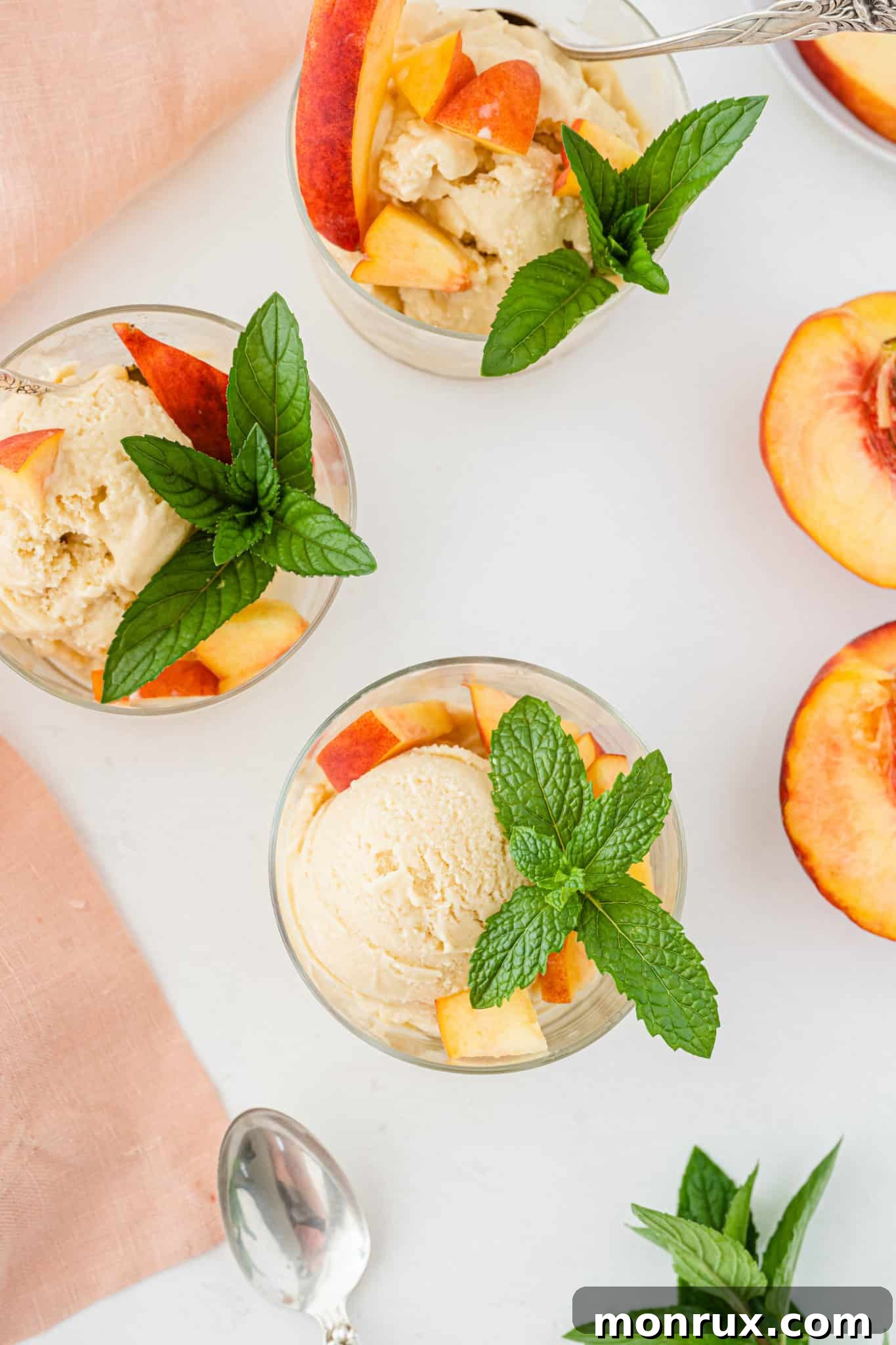 Three bowls of vibrant vegan peach ice cream artfully arranged on a rustic wooden table.