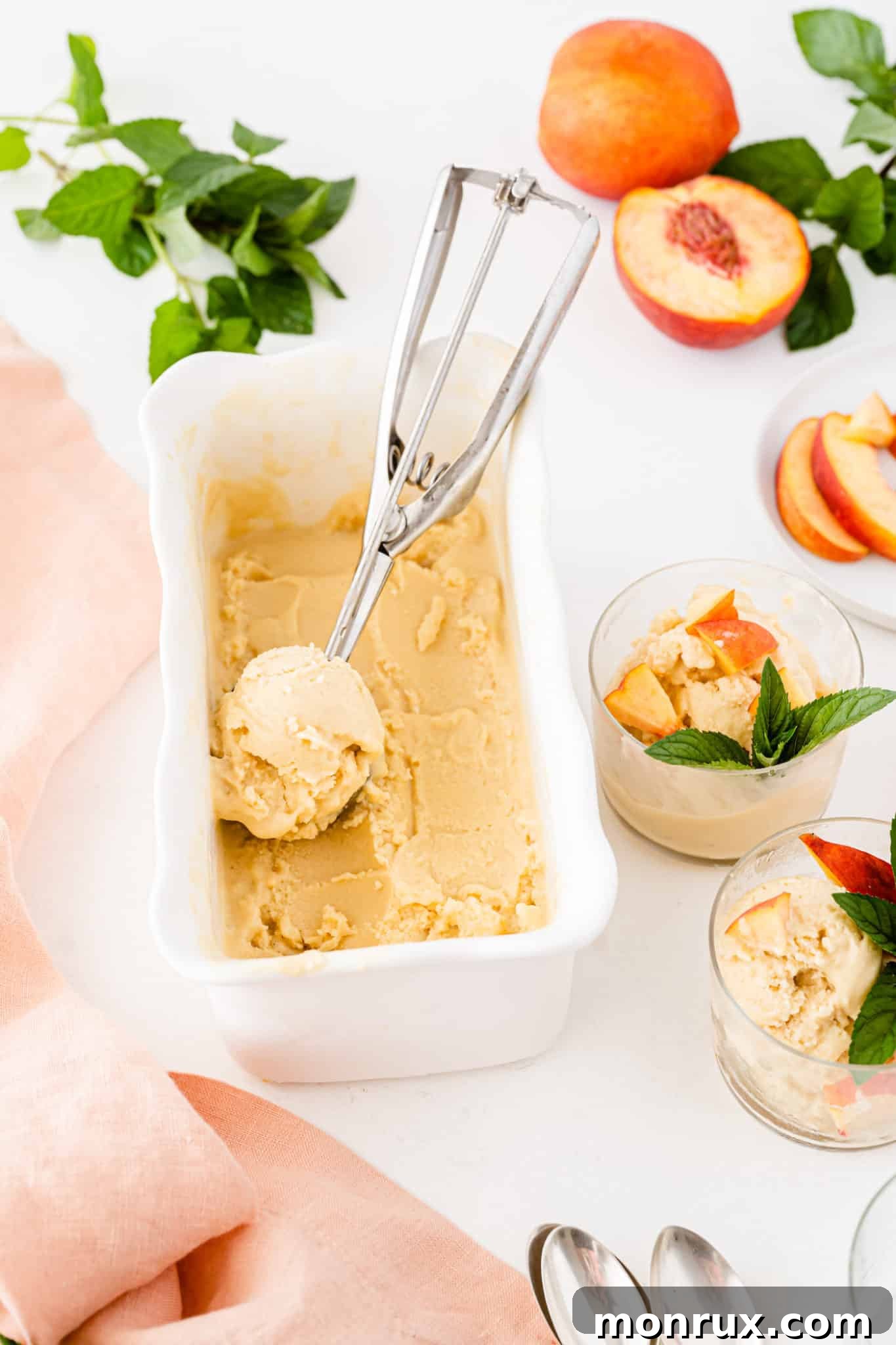 Creamy homemade ice cream in a white container, with an ice cream scooper resting on the side, ready to be served.