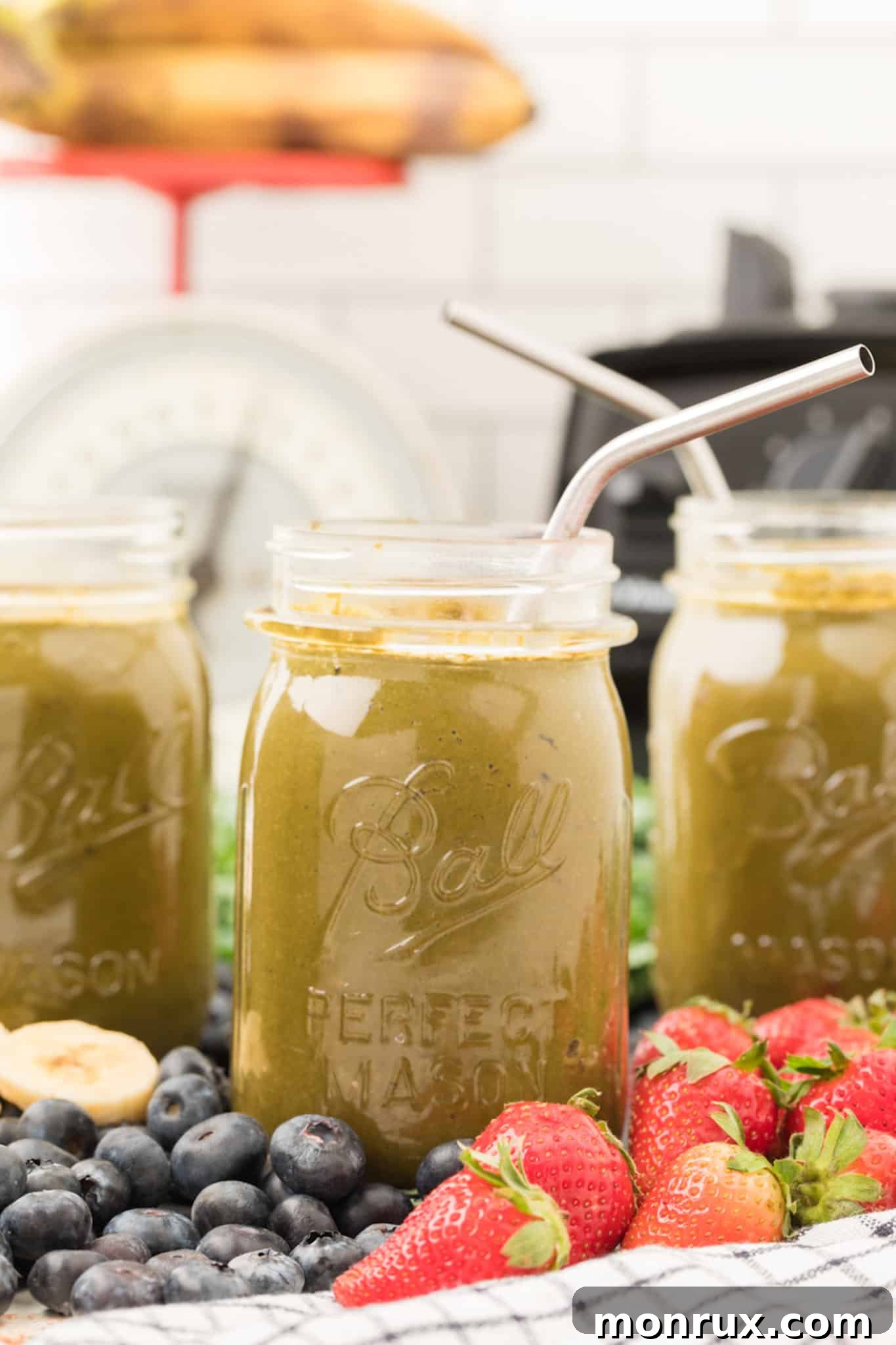 Delicious collard green smoothie served in a glass jar with metal straws, ready to enjoy.