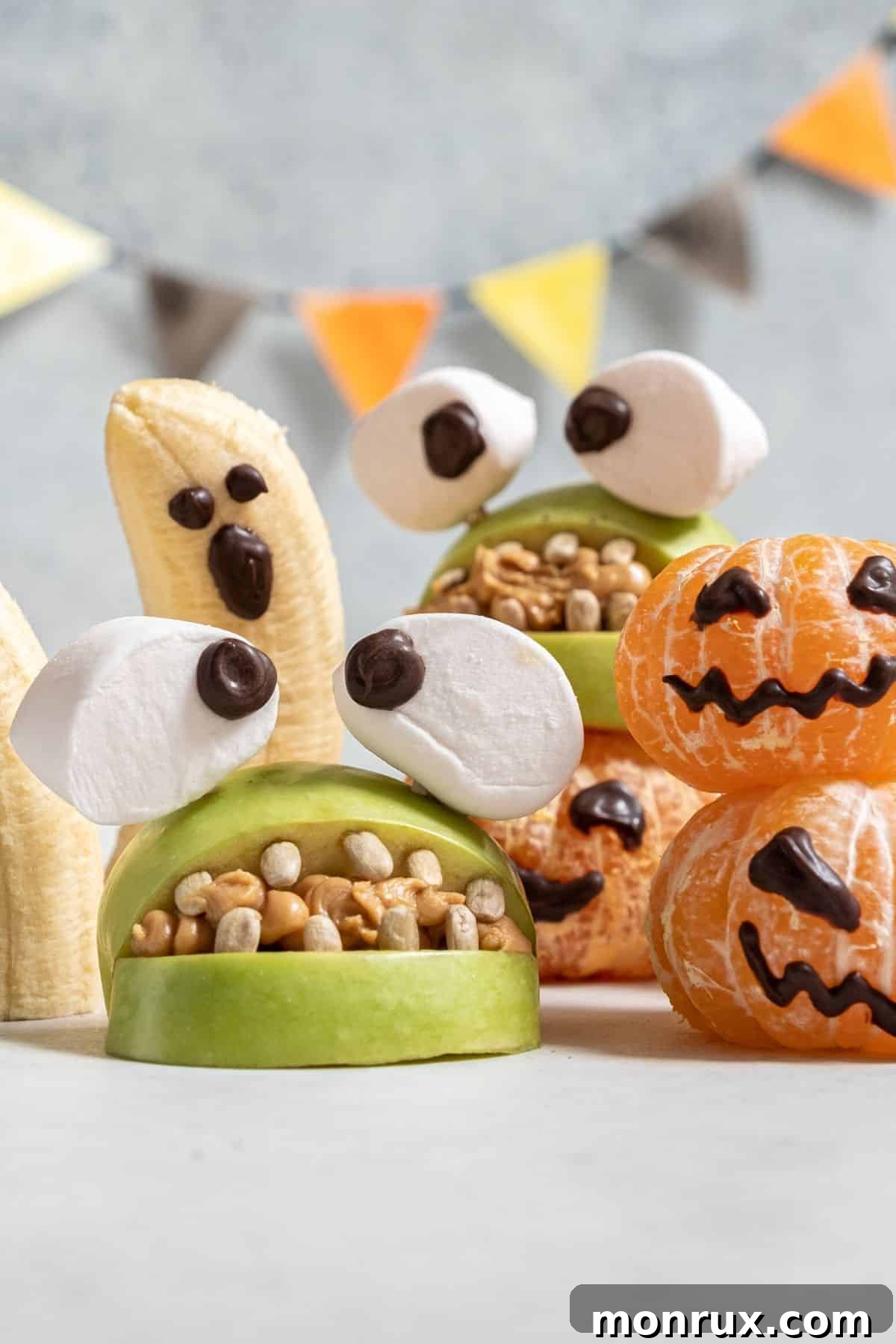 A festive tray of healthy Halloween fruit snacks, including orange slices, grapes, and apple slices with spooky faces.