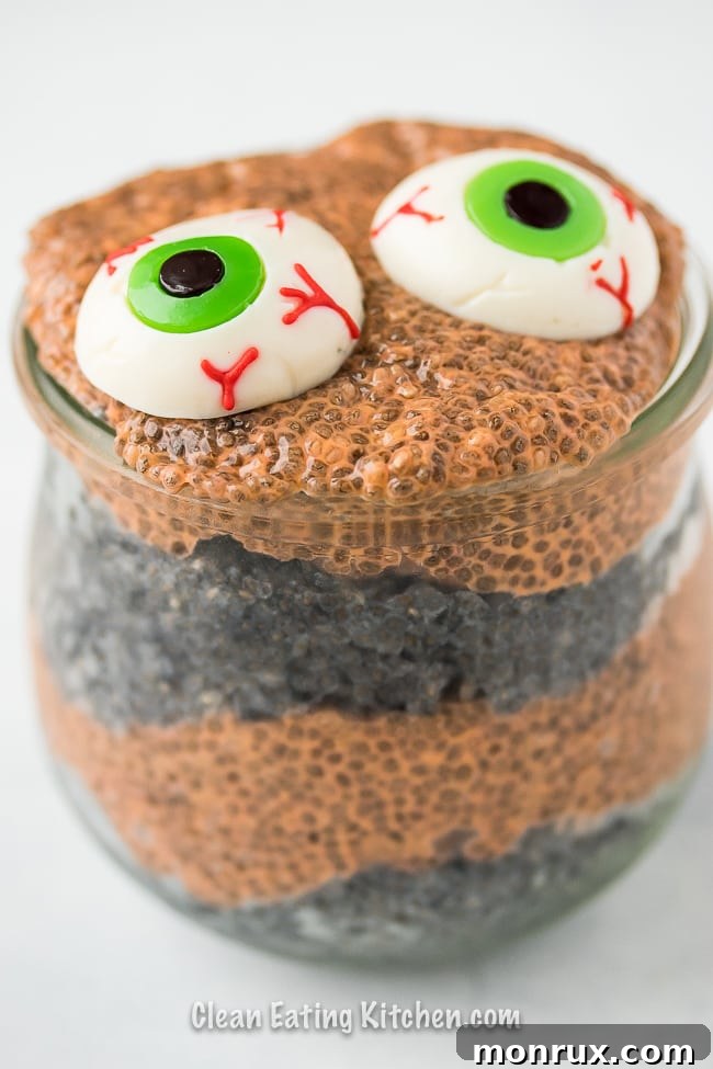 Layers of orange and black chia pudding, topped with a single spooky gummy eyeball.