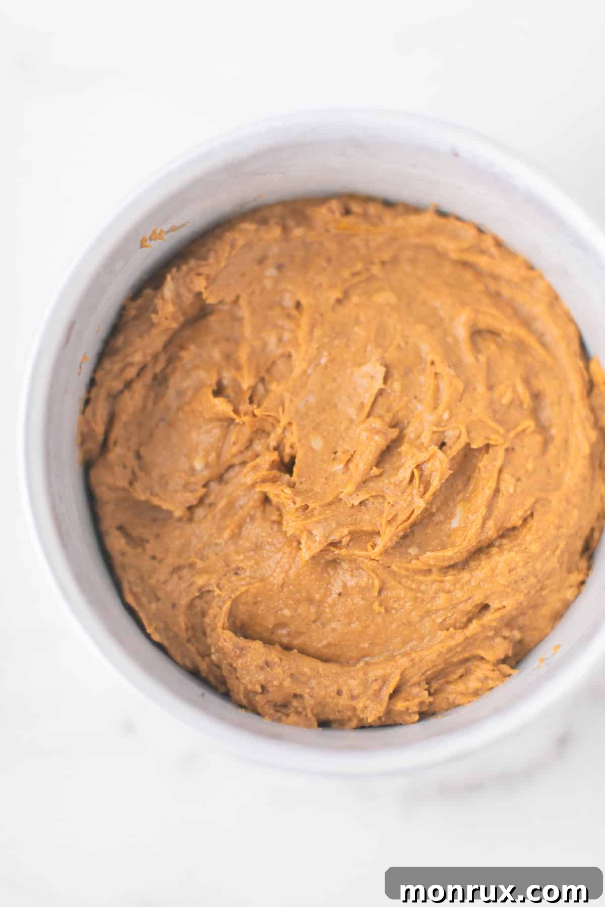 Close-up photo of the smooth pumpkin cake batter perfectly settled in the prepared cake pan, glistening and ready for its transformation in the Instant Pot.