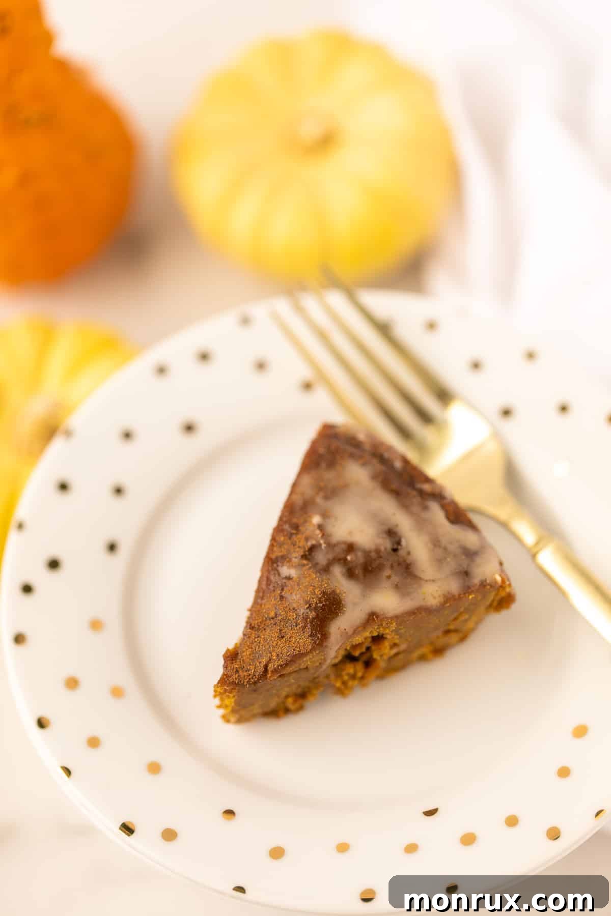 A mouth-watering slice of freshly baked Instant Pot Pumpkin Spice Cake, elegantly drizzled with sweet glaze, invitingly placed next to a golden fork.