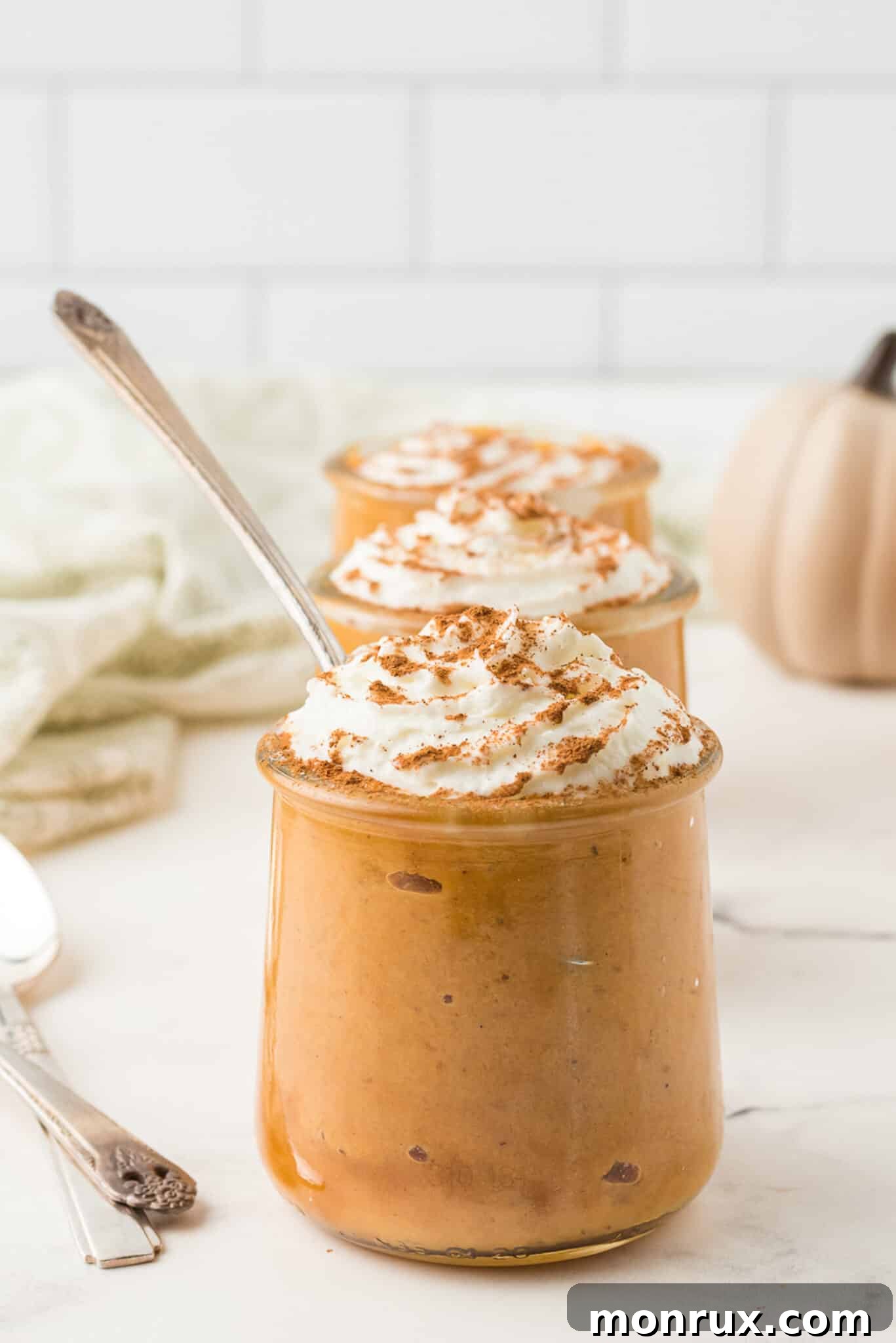 Delicious Instant Pot Pumpkin Pudding served in individual jars, topped with a dollop of dairy-free whipped cream, garnished with a sprinkle of cinnamon.