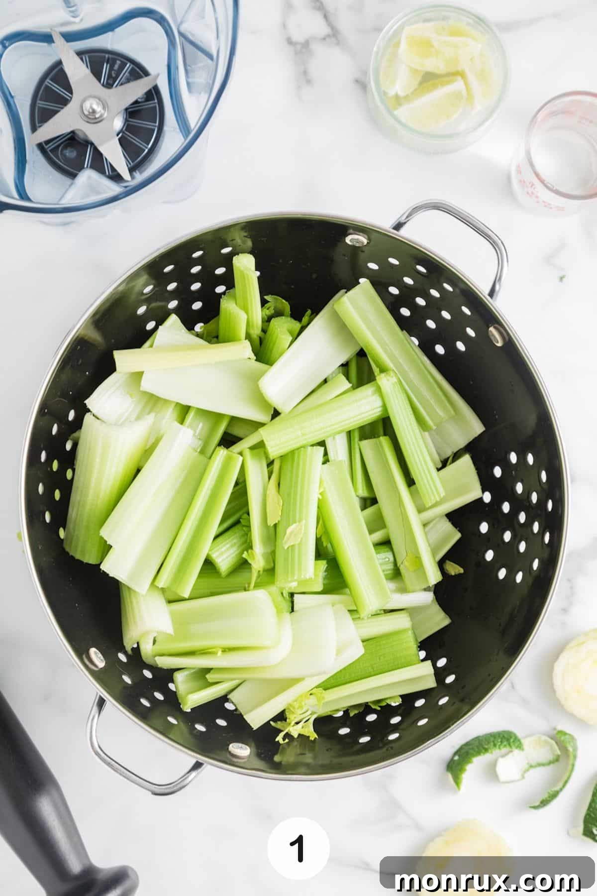 Washing fresh celery stalks in a colander under running water.