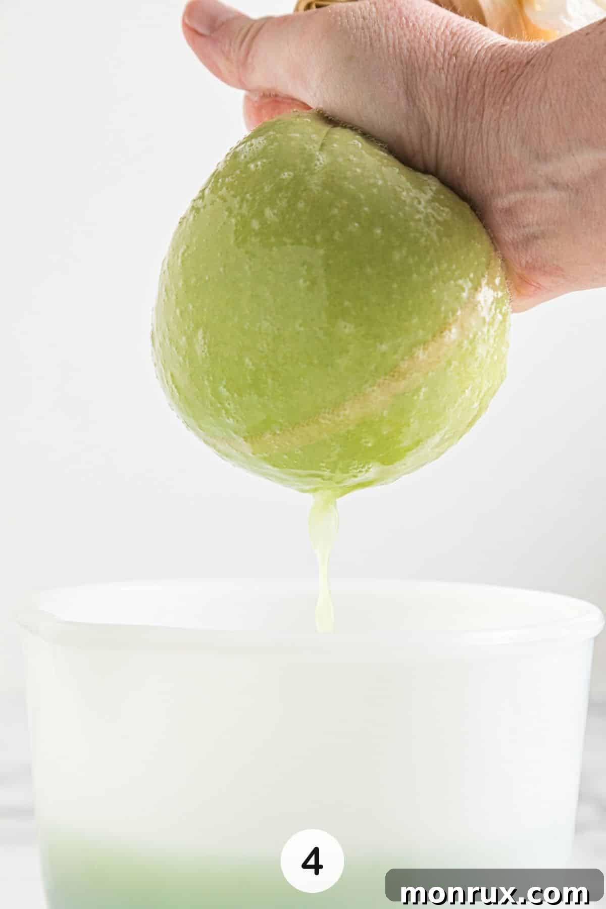 Straining freshly blended celery pulp through a nut milk bag into a glass pitcher.