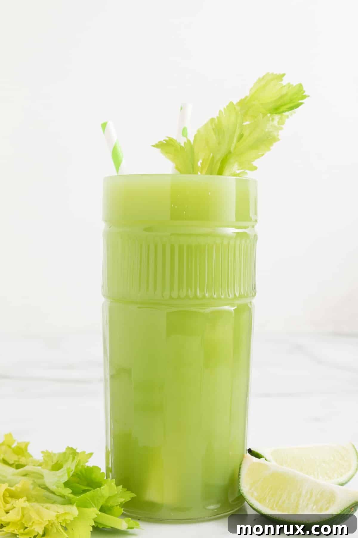 A large glass of celery lime juice, garnished with fresh celery leaves, looking refreshing.