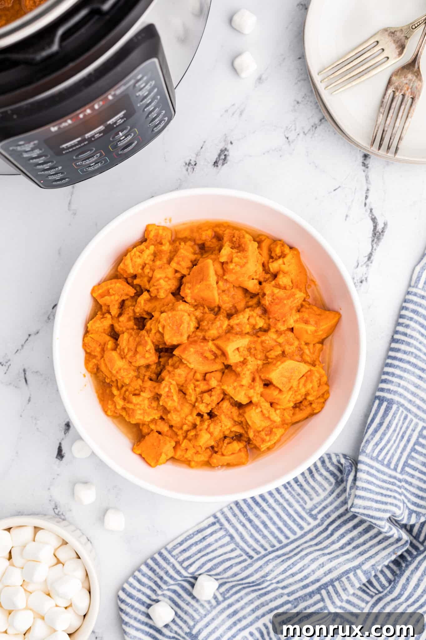 A serving bowl filled with beautifully candied yams, without marshmallows, presented warm.