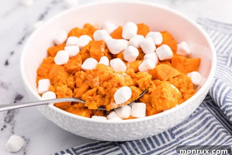 A white serving bowl with candied yams topped with marshmallows.