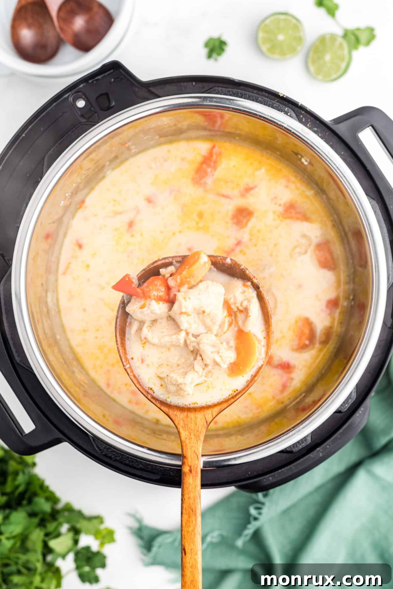 A ladle serving creamy Thai Chicken Curry Soup from an Instant Pot into a bowl, with the pot full of soup.