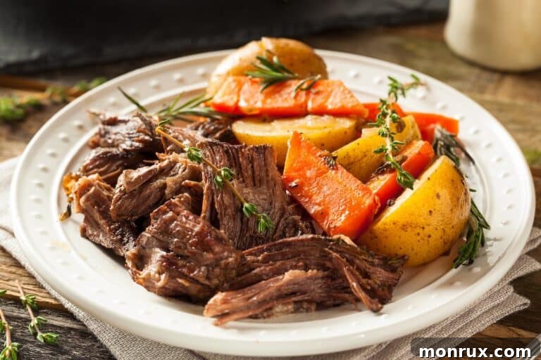 A mouth-watering slow cooker tri tip roast on a plate, surrounded by vegetables.