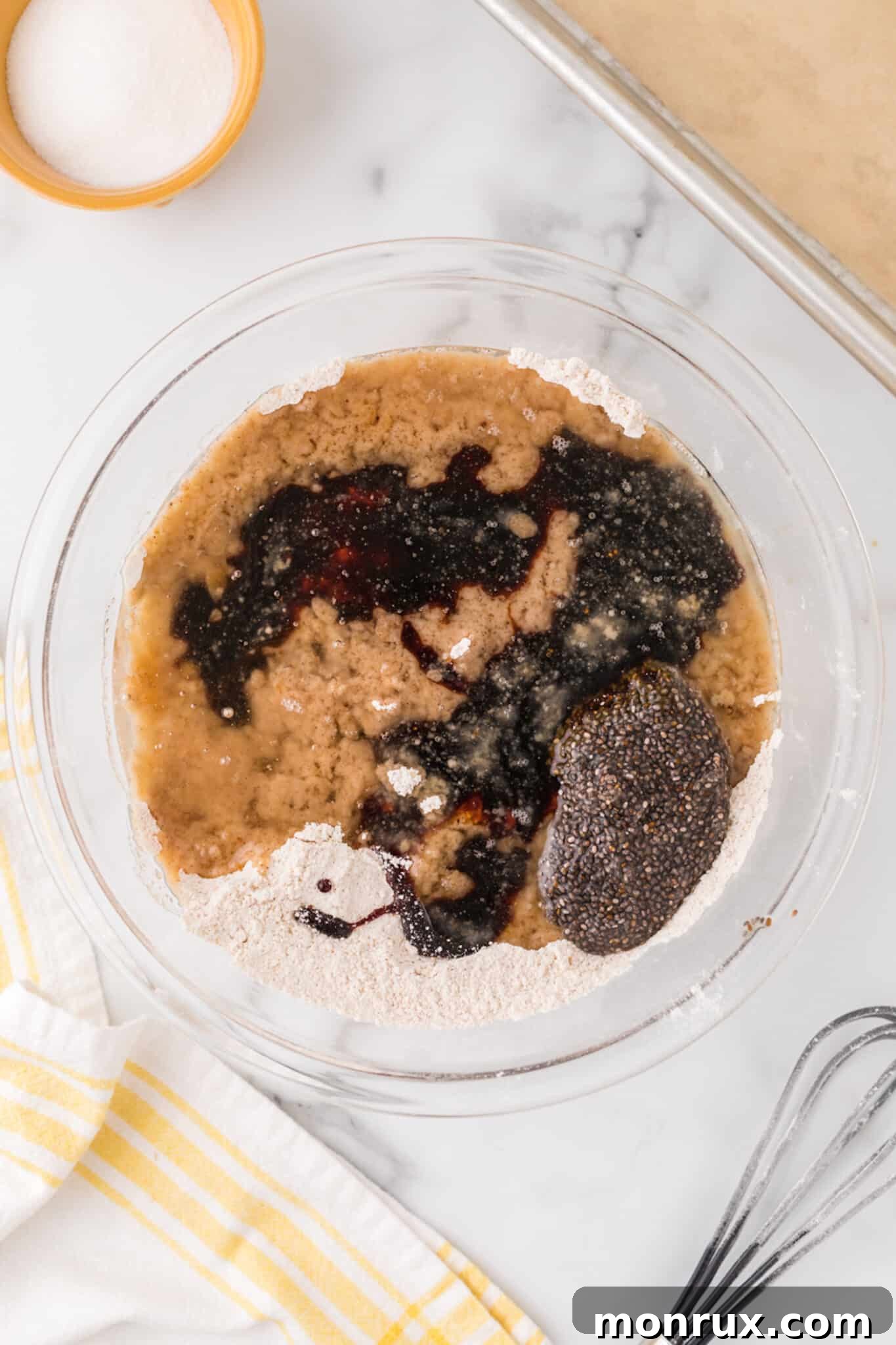 Wet ingredients, including melted coconut oil and dark molasses, being poured into a bowl of dry cookie ingredients.