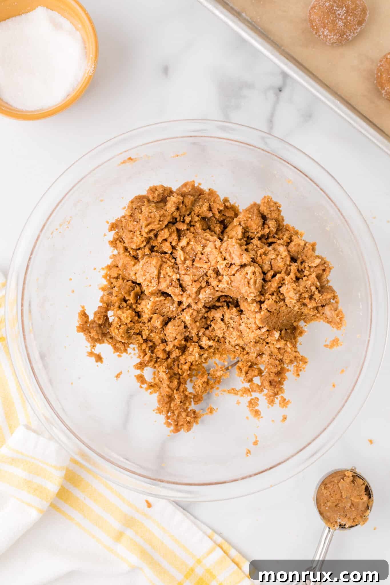 Close-up of a bowl containing freshly mixed vegan gingersnap cookie dough, showcasing its rich, dark brown color and soft consistency.