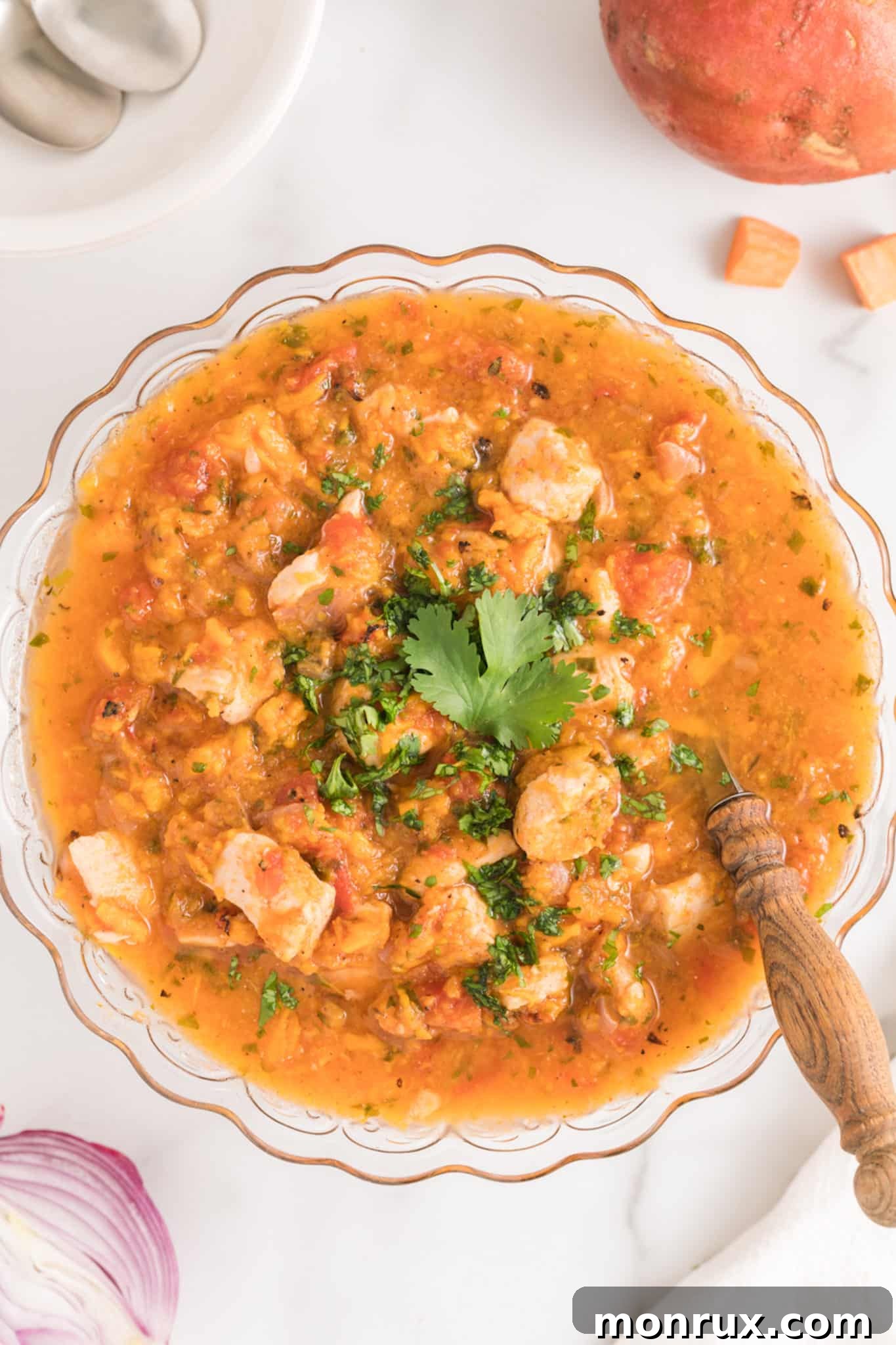 Instant Pot Sweet Potato Chicken and Sweet Potato stew in a glass serving bowl, garnished with fresh cilantro.