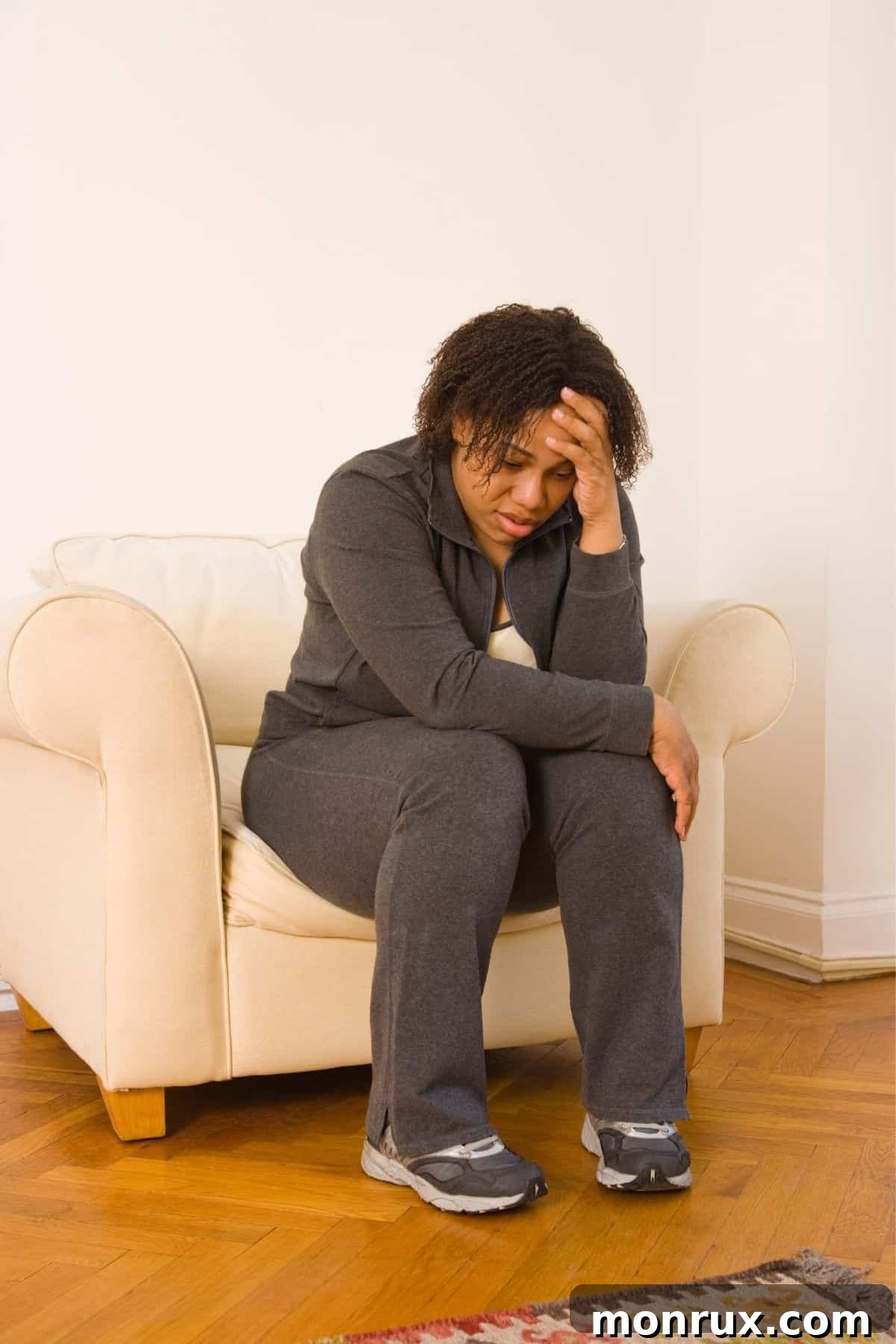 A tired woman sitting on a chair, holding her head, symbolizing exhaustion.