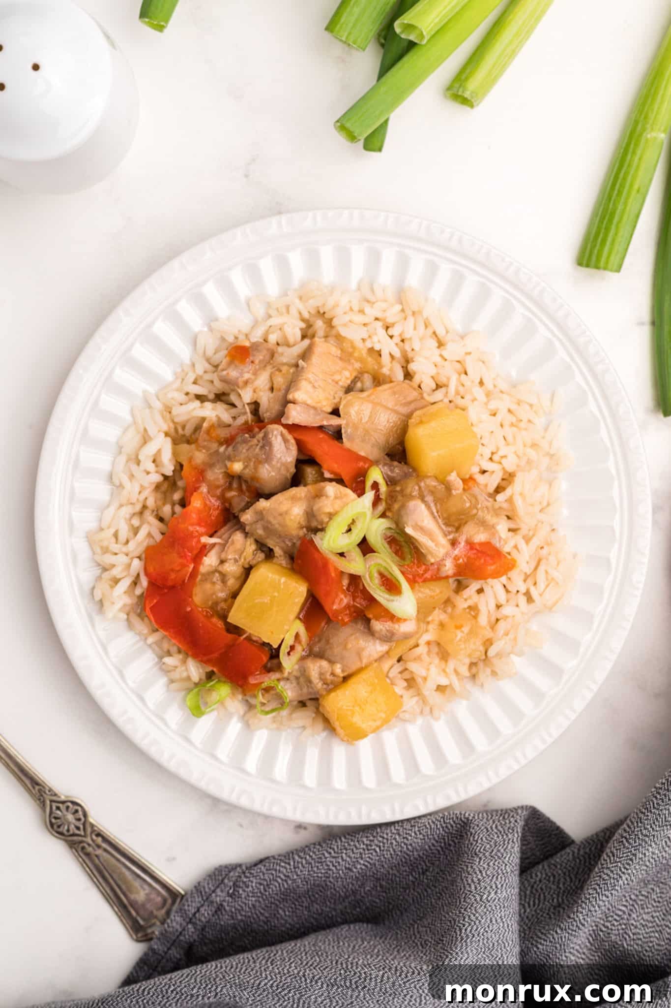 Plate of pineapple chicken with vegetables and steamed rice.