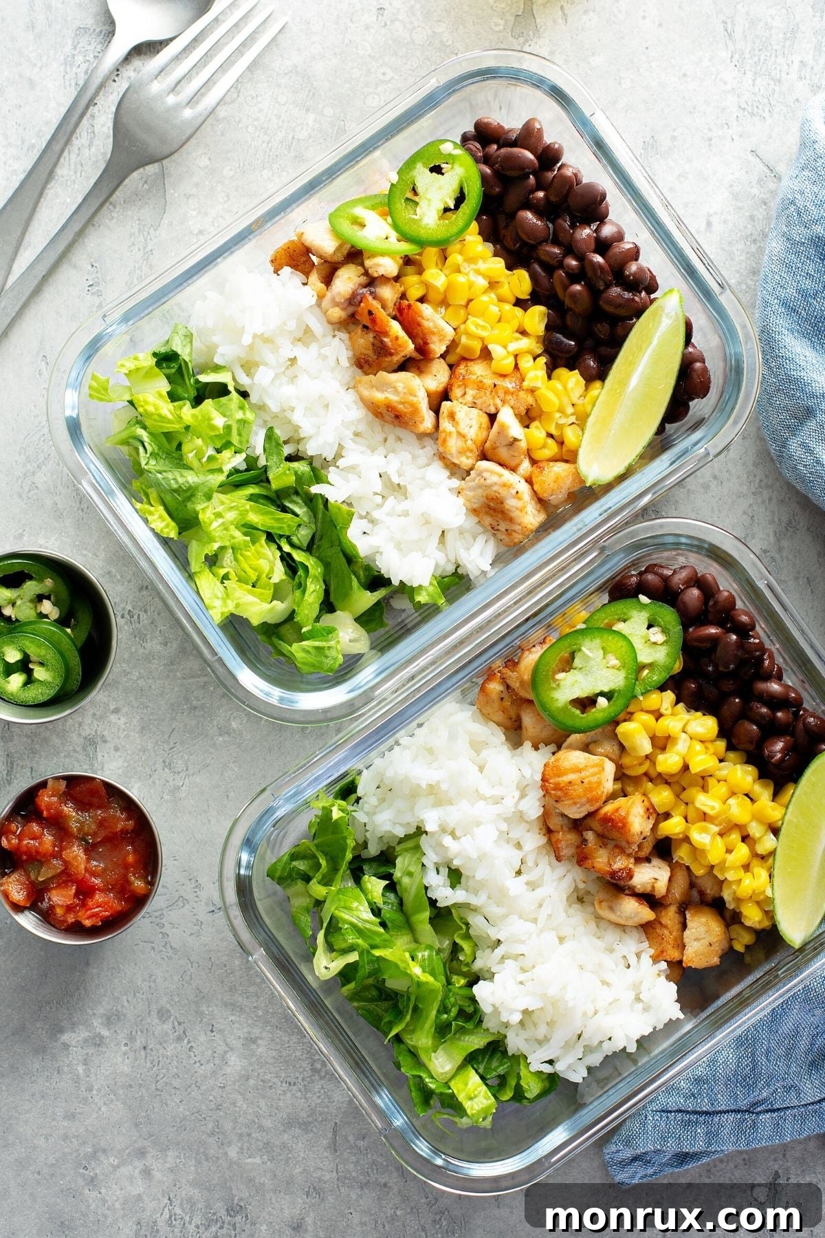Two glass bowls filled with healthy meal prep featuring chicken, rice, and black beans, ready for the week.