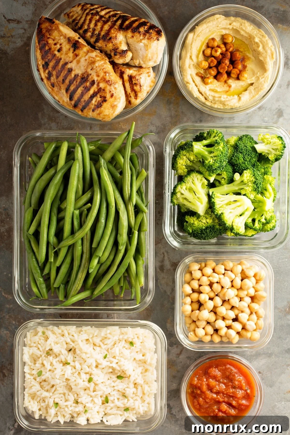 A vibrant buffet-style meal prep featuring various vegetables, grilled chicken, and grains, ready to be combined.