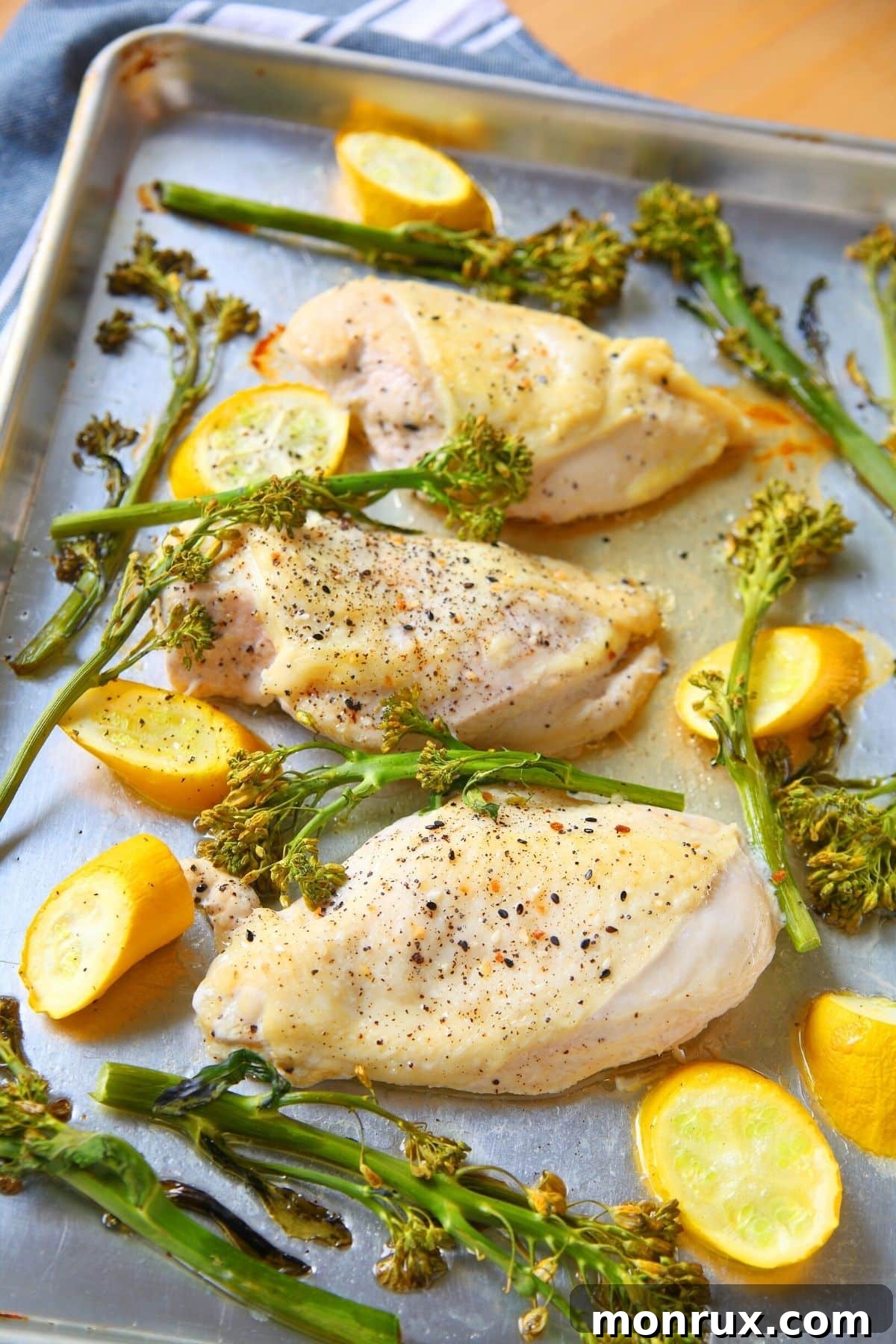 A sheet pan with baked lemon chicken and vibrant broccoli, illustrating efficient oven multi-tasking.