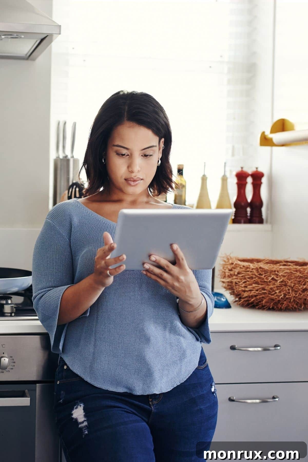 A woman happily planning her meals on a tablet in her bright kitchen, embodying organized meal preparation.
