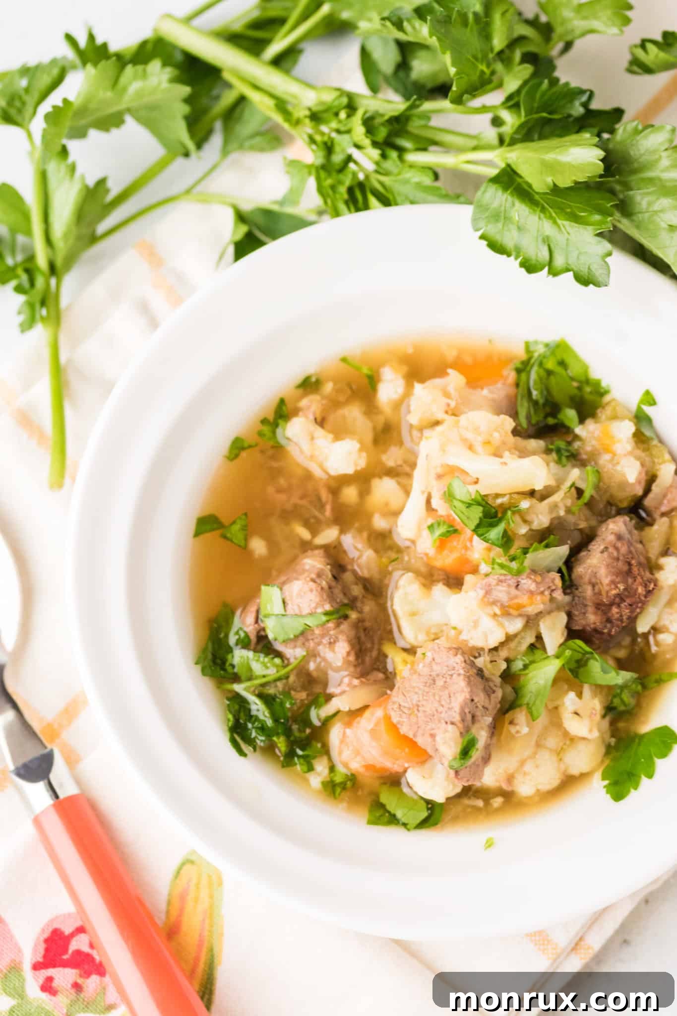 A beautiful bowl of venison stew, rich with tender meat and colorful vegetables, served on a rustic table.