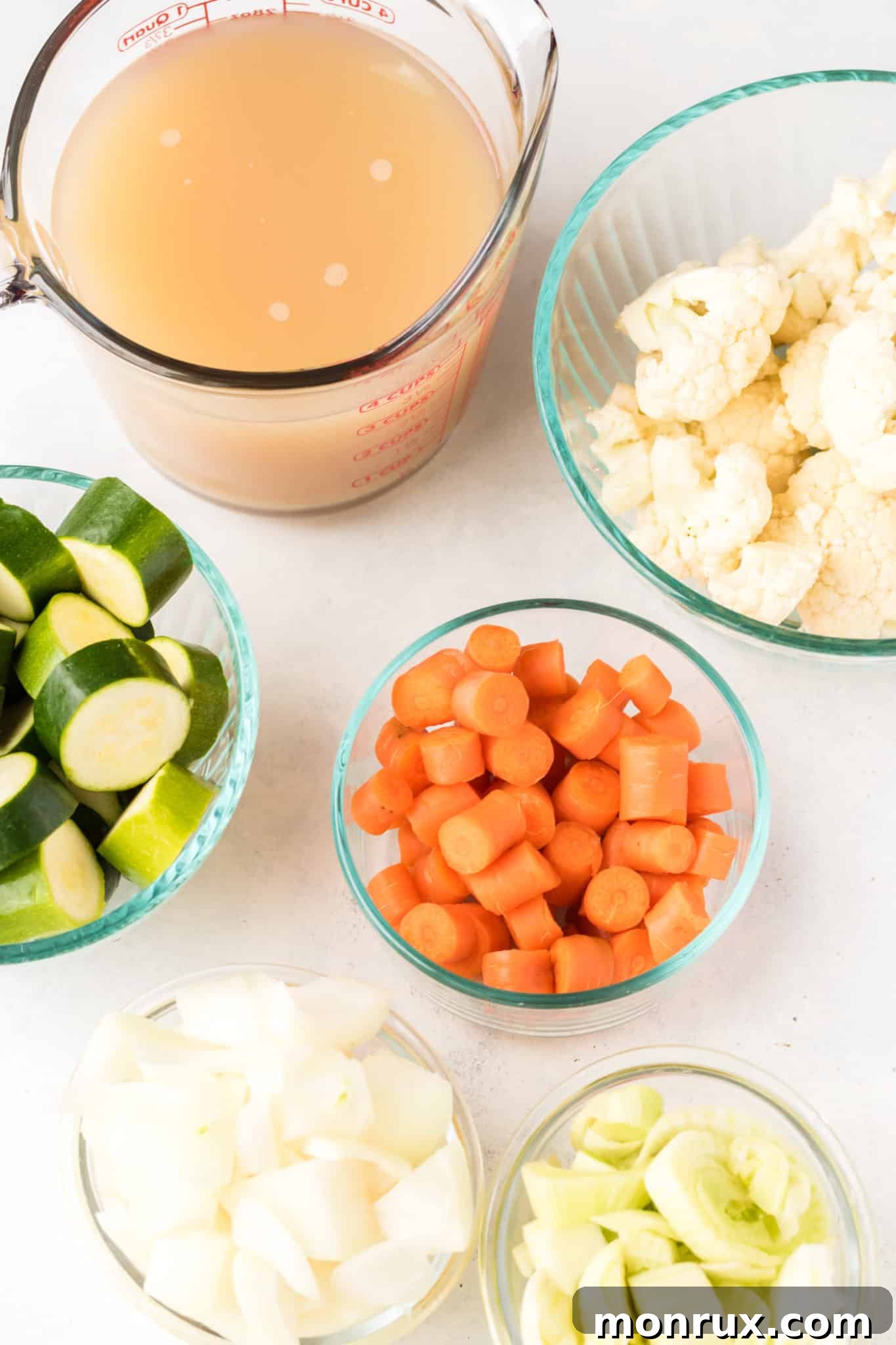 A colorful array of fresh ingredients for venison stew, including venison chunks, onions, carrots, zucchini, fennel, and garlic.