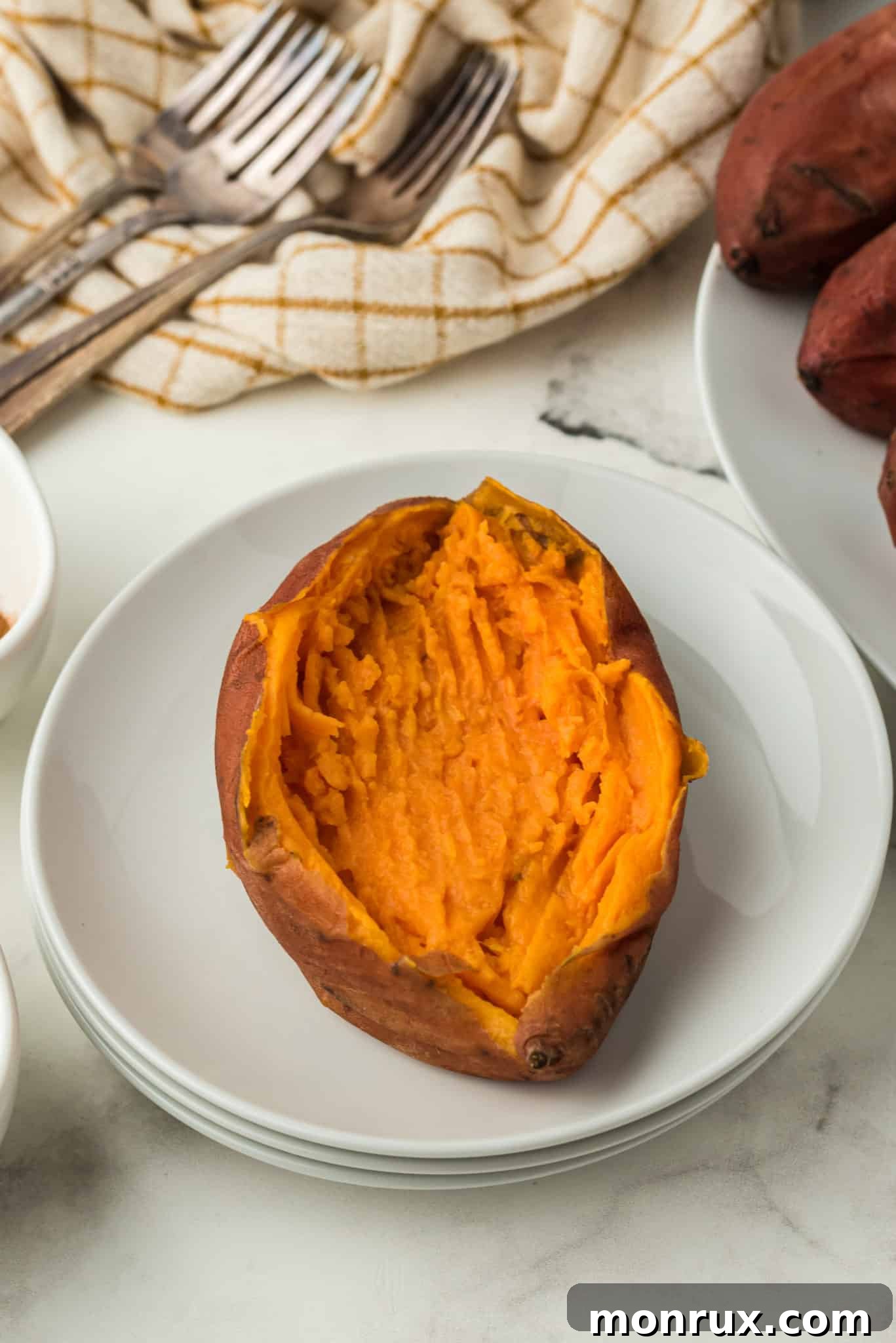 Whole baked sweet potato on a plate, ready to be topped.