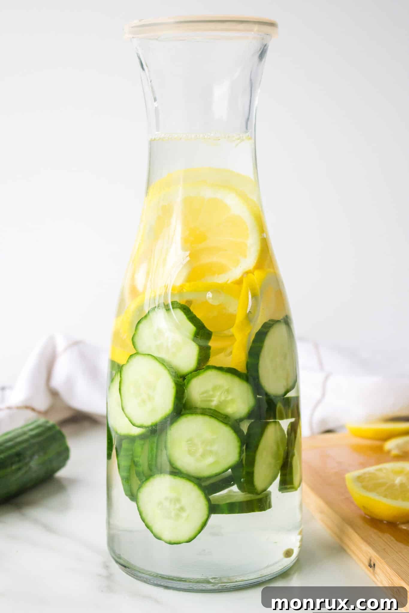 A glass carafe filled with refreshing cucumber, ginger, and lemon infused water, perfect for healthy hydration.