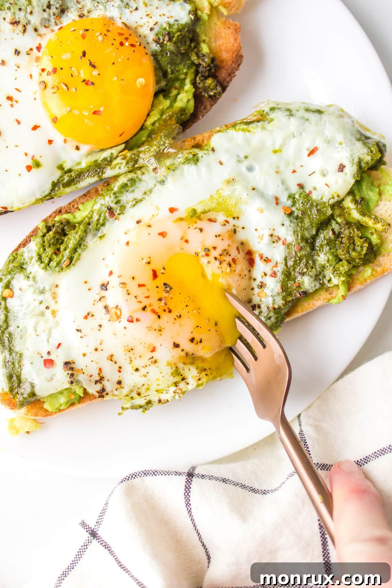 A delicious plate of pesto eggs served on avocado toast with a fork, representing a meal rich in healthy fats.