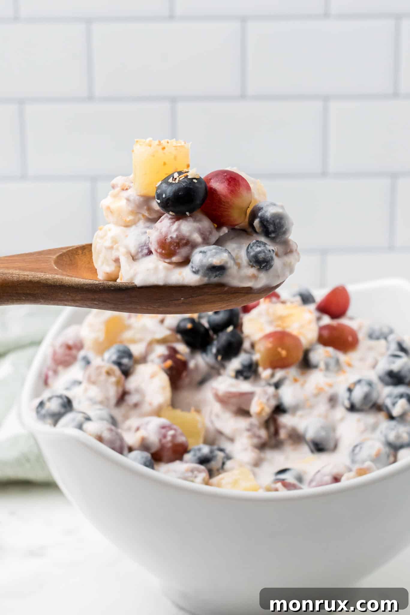 A spoonful of vibrant Ambrosia Salad, made with fresh fruit and naturally sweetened, as a healthy dessert alternative.