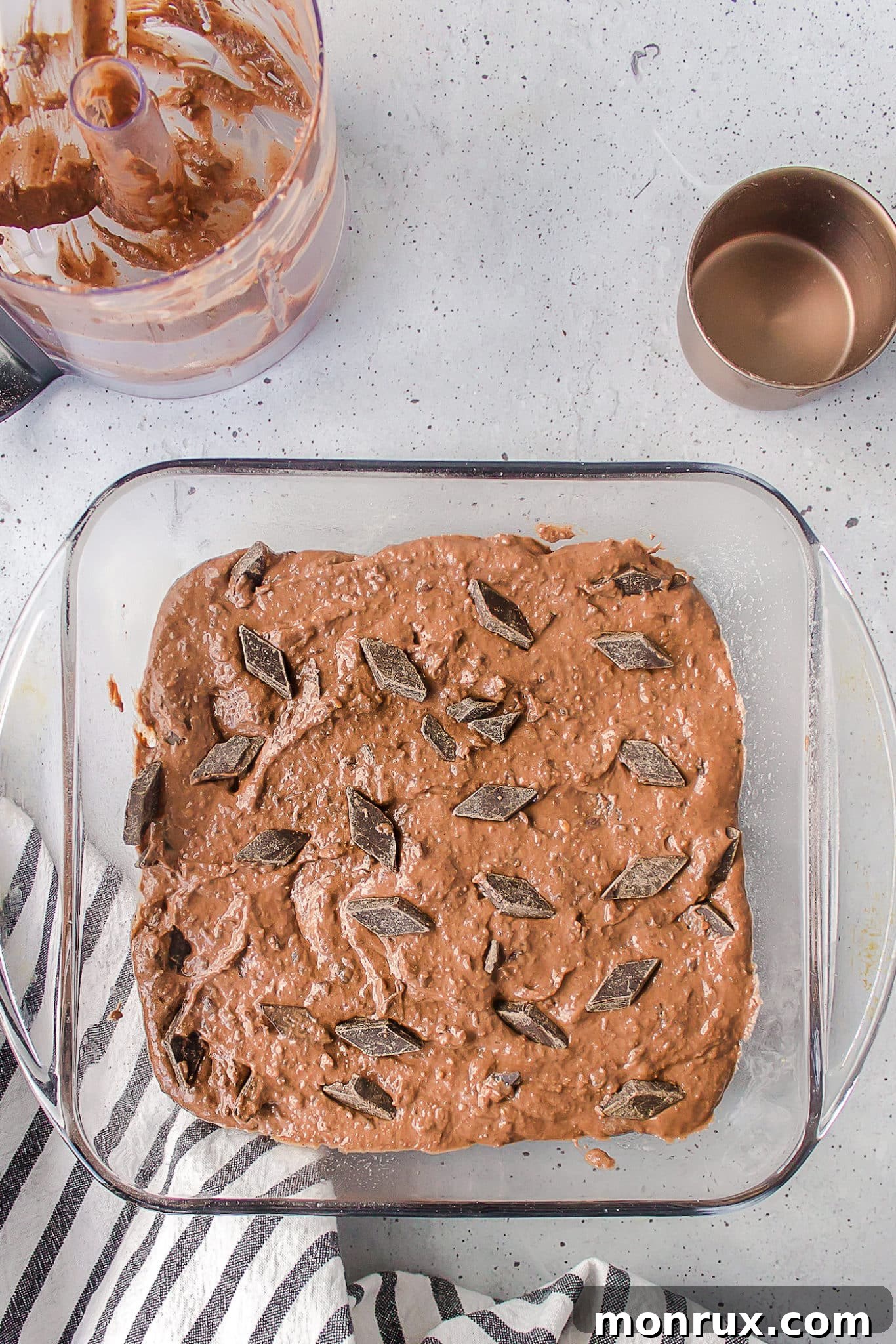 Thick, dark chocolate black bean brownie batter spread evenly in a square baking dish, ready for baking.