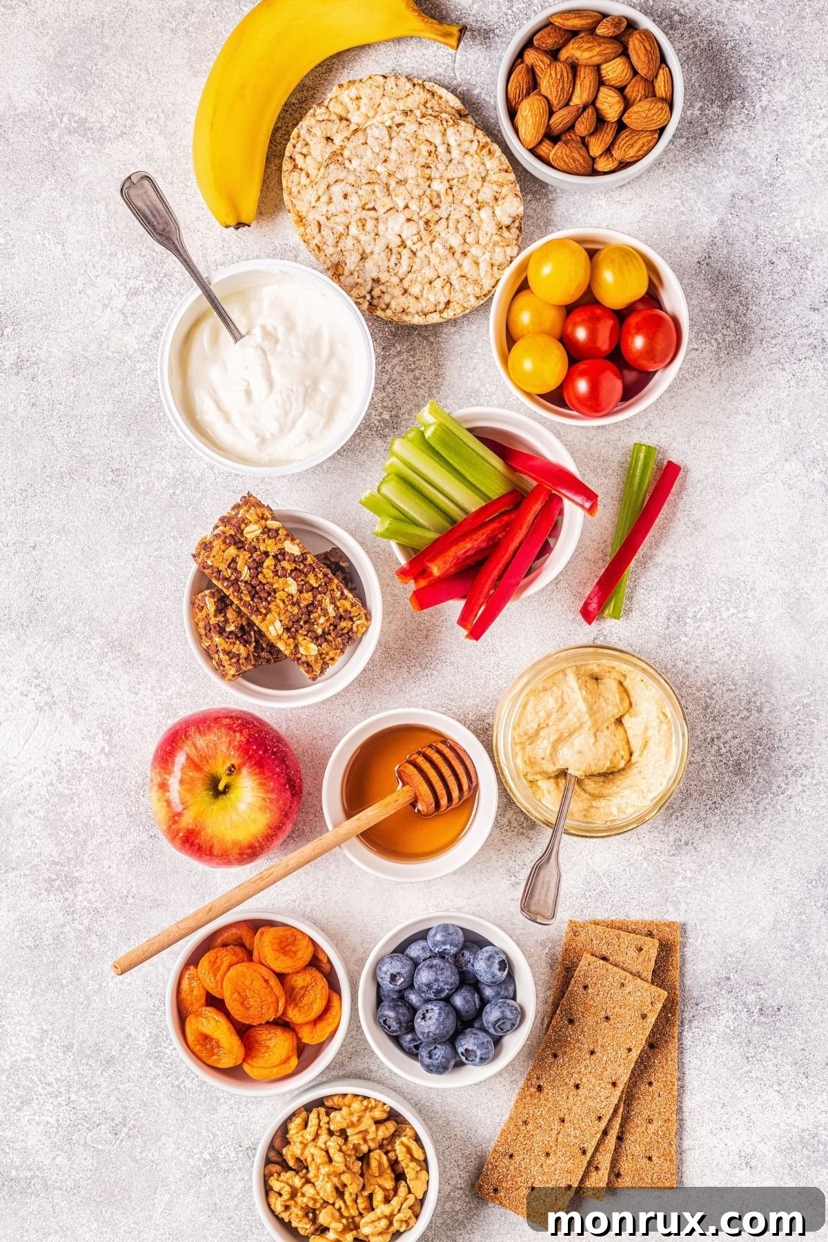 A counter full of healthy snacks, including fruit, nuts, and clean crackers