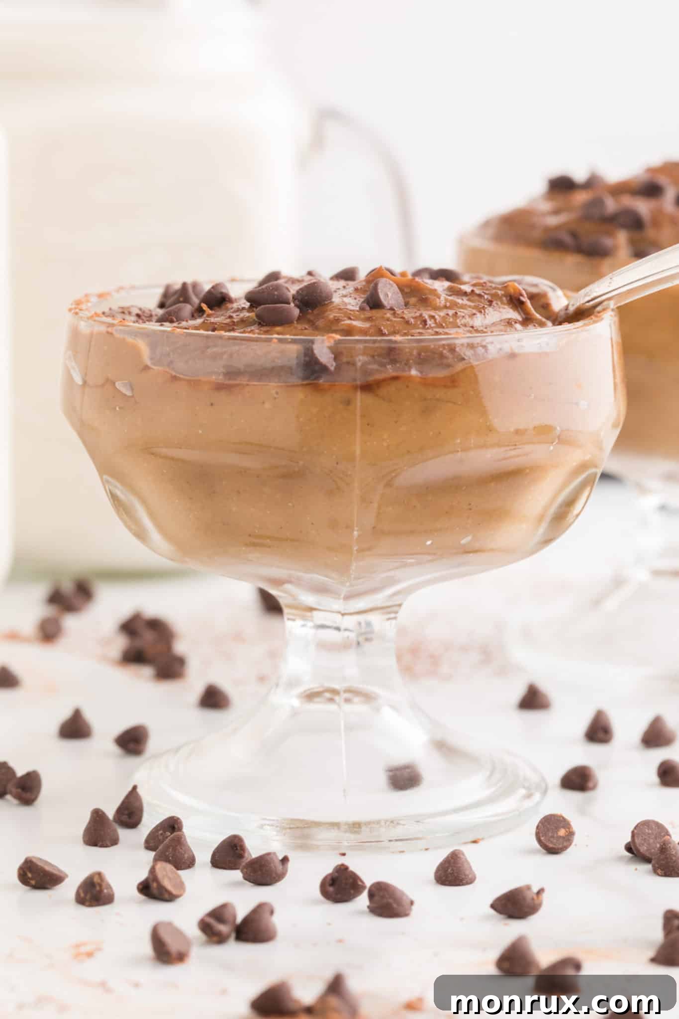A large parfait cup is generously filled with creamy chocolate avocado pudding, artfully topped with an abundance of chocolate chips for a rich and inviting presentation.