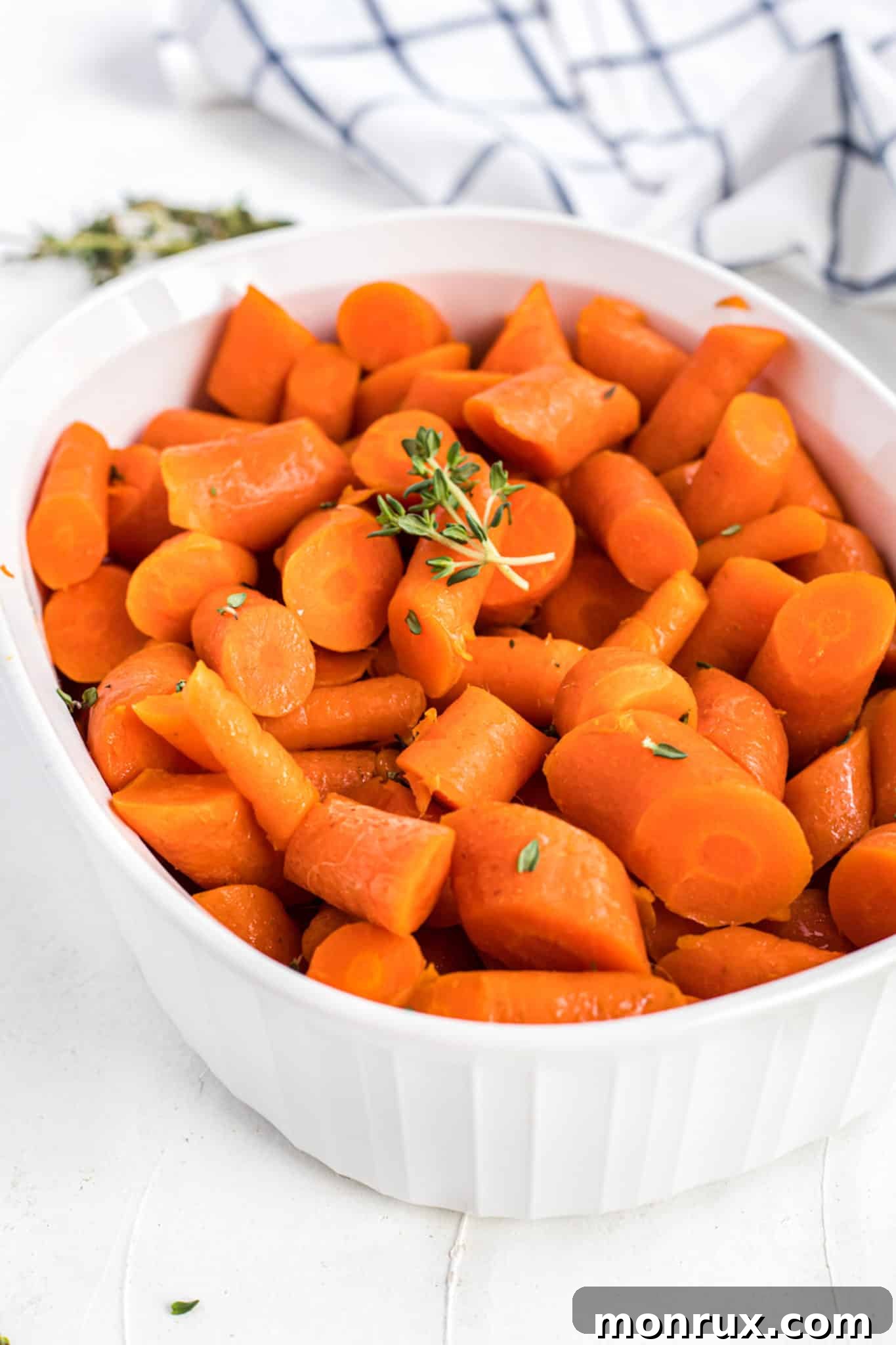 Instant pot cooked carrots in white casserole dish with thyme.