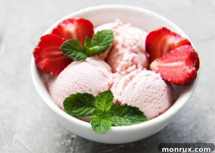 Bowl of pink strawberry ice cream with fresh strawberries