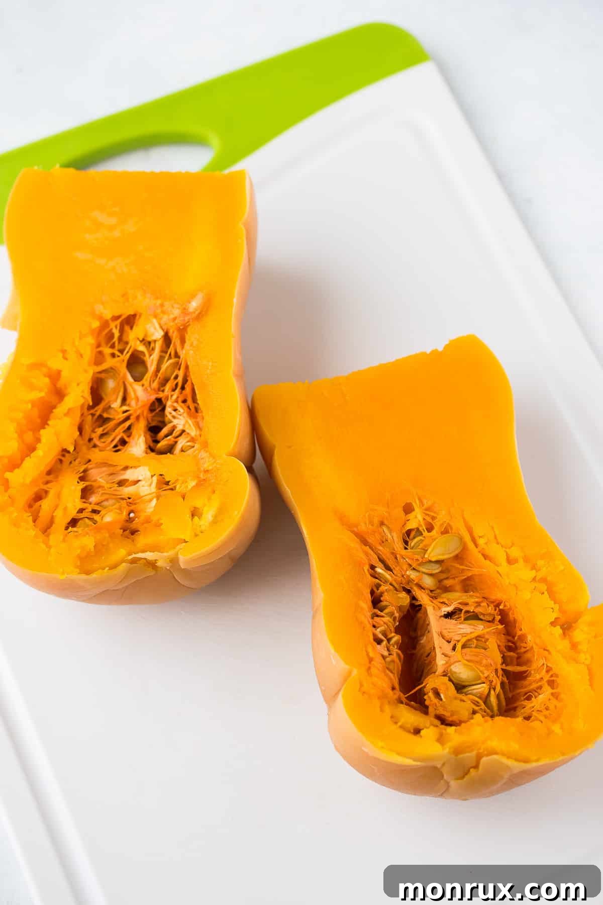 cooked butternut squash cut in half lengthwise on a cutting board.